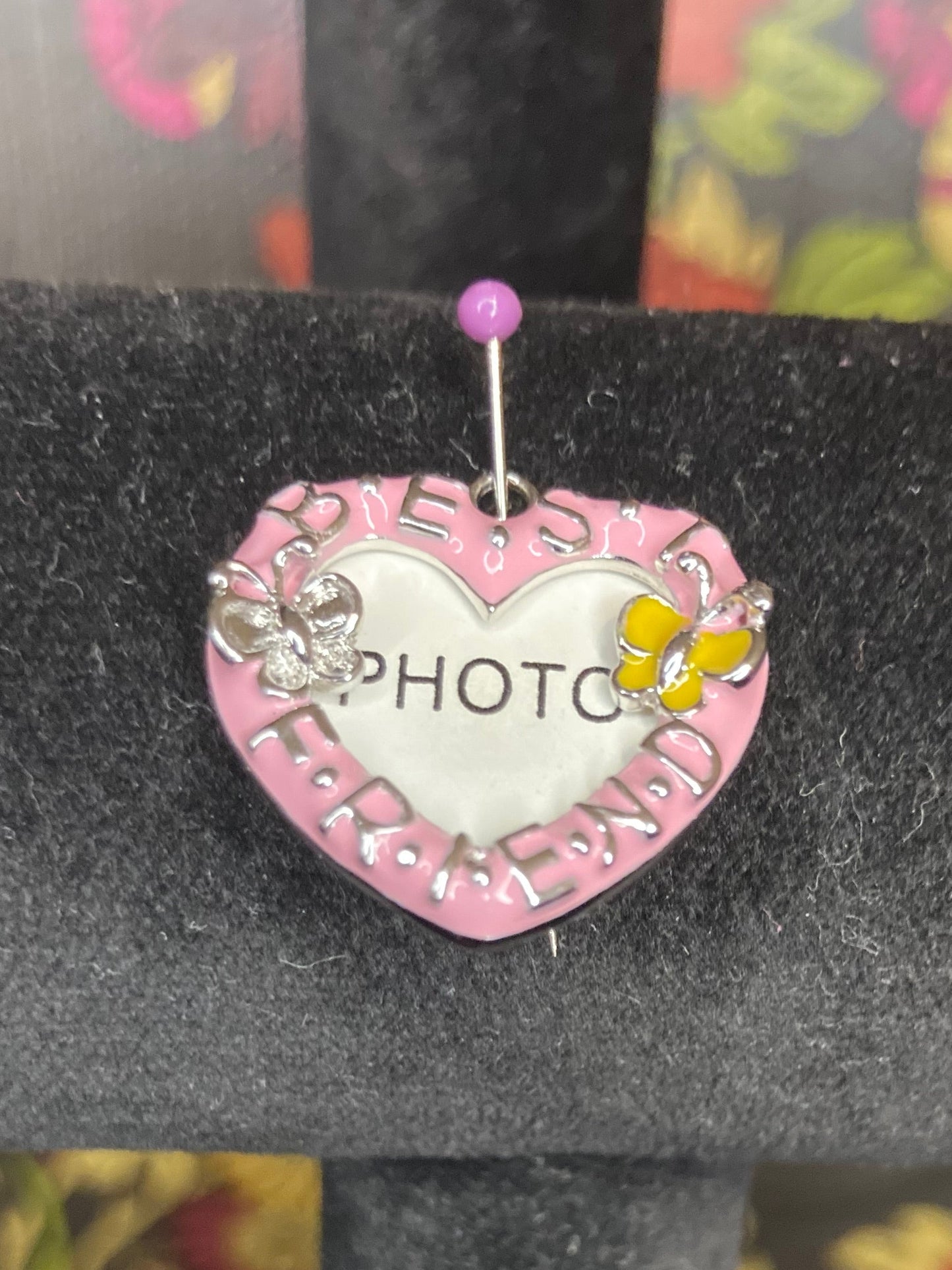 Pink heart-shaped earring with 'PHOTO' on a black stand