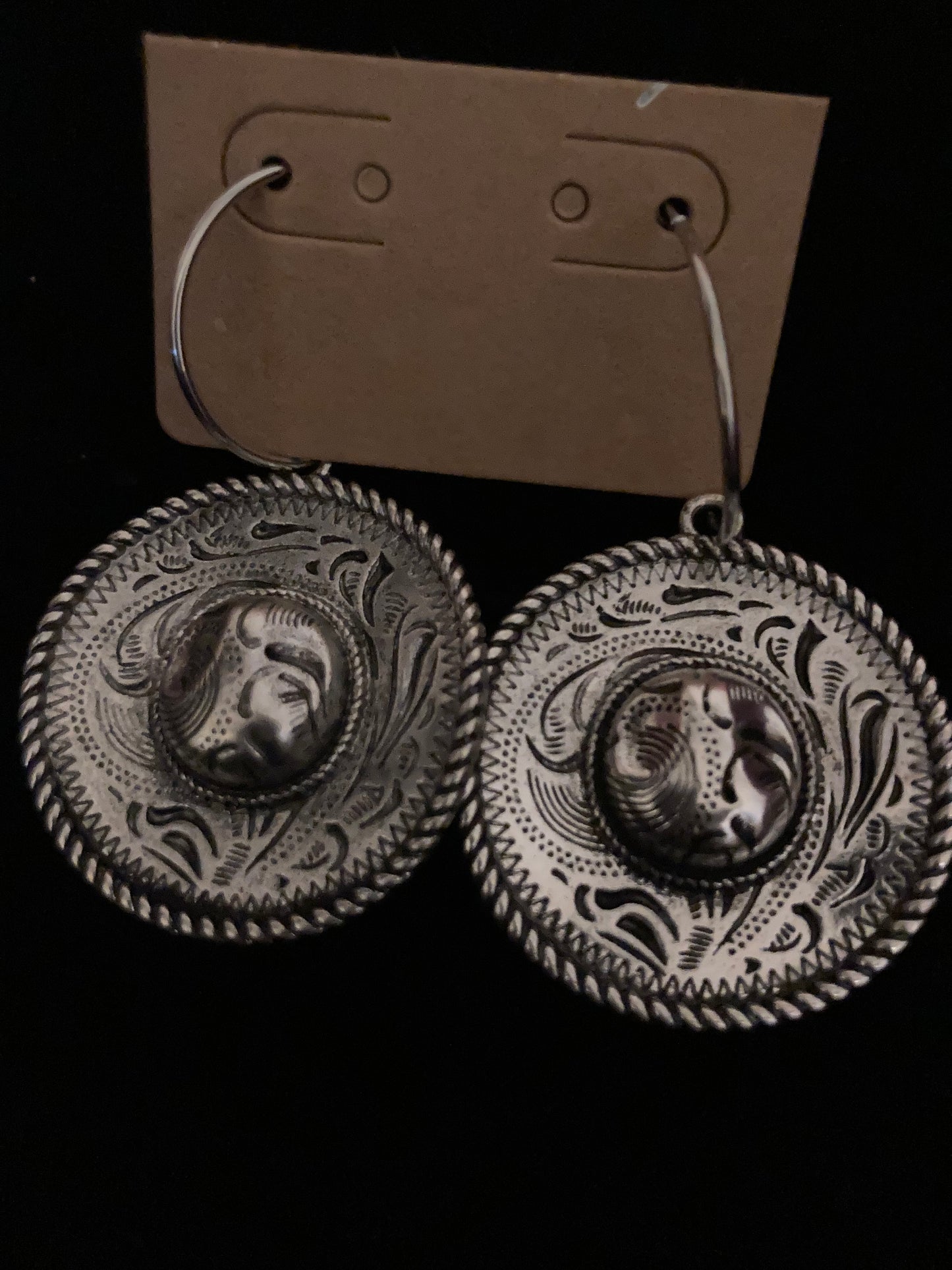 Pair of silver earrings with intricate designs on a black background