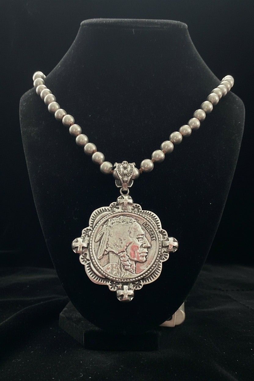Decorative necklace with a pendant on a black stand against a pink background