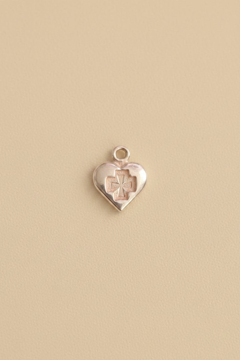 Heart-shaped charm with a cross design on a cream background