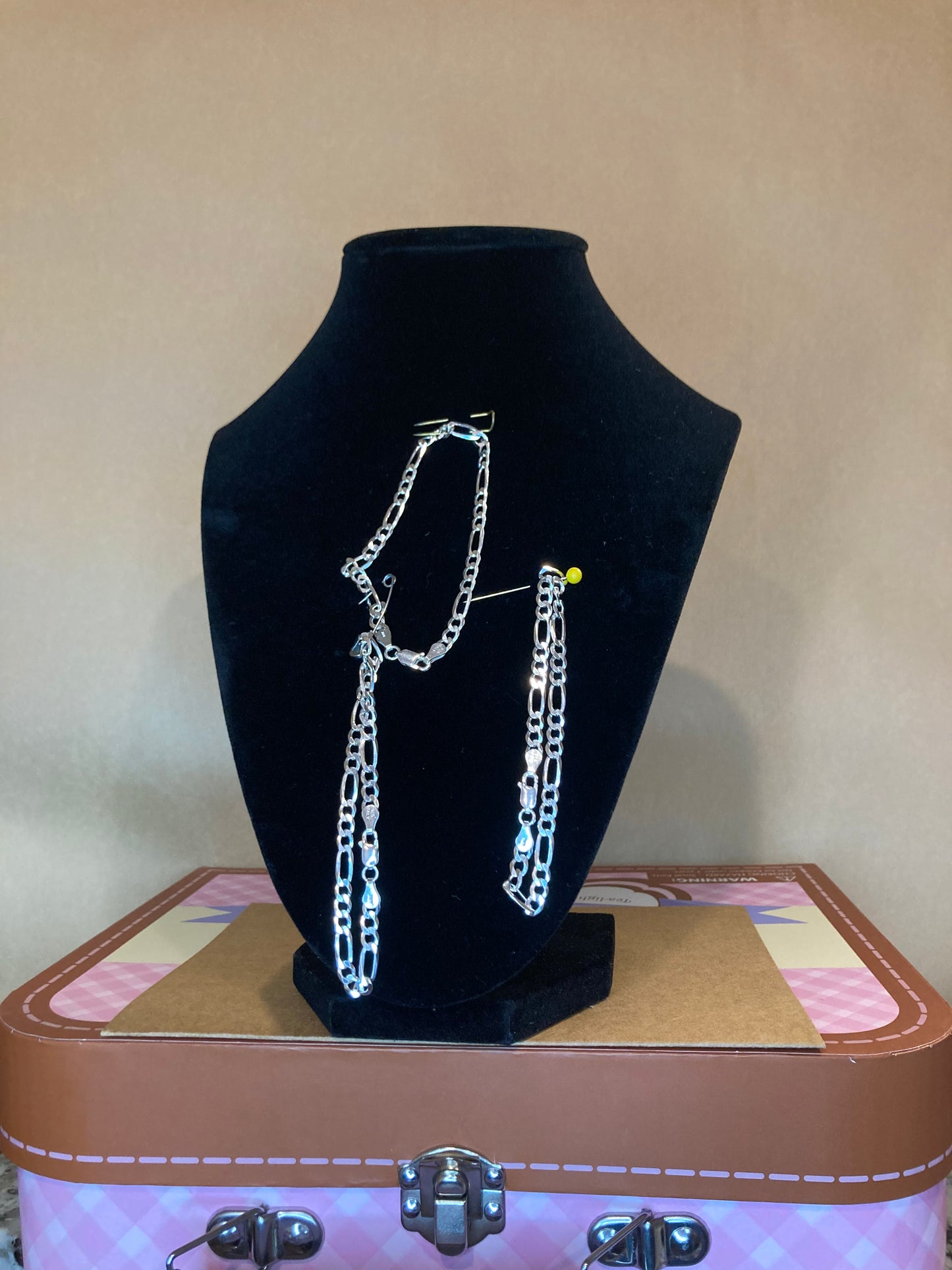 Silver Bracelet on a black velvet stand with a pink and brown box in the background.