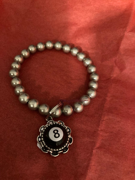 Silver Chunky Beaded bracelet with a 8 Ball charm on a red background