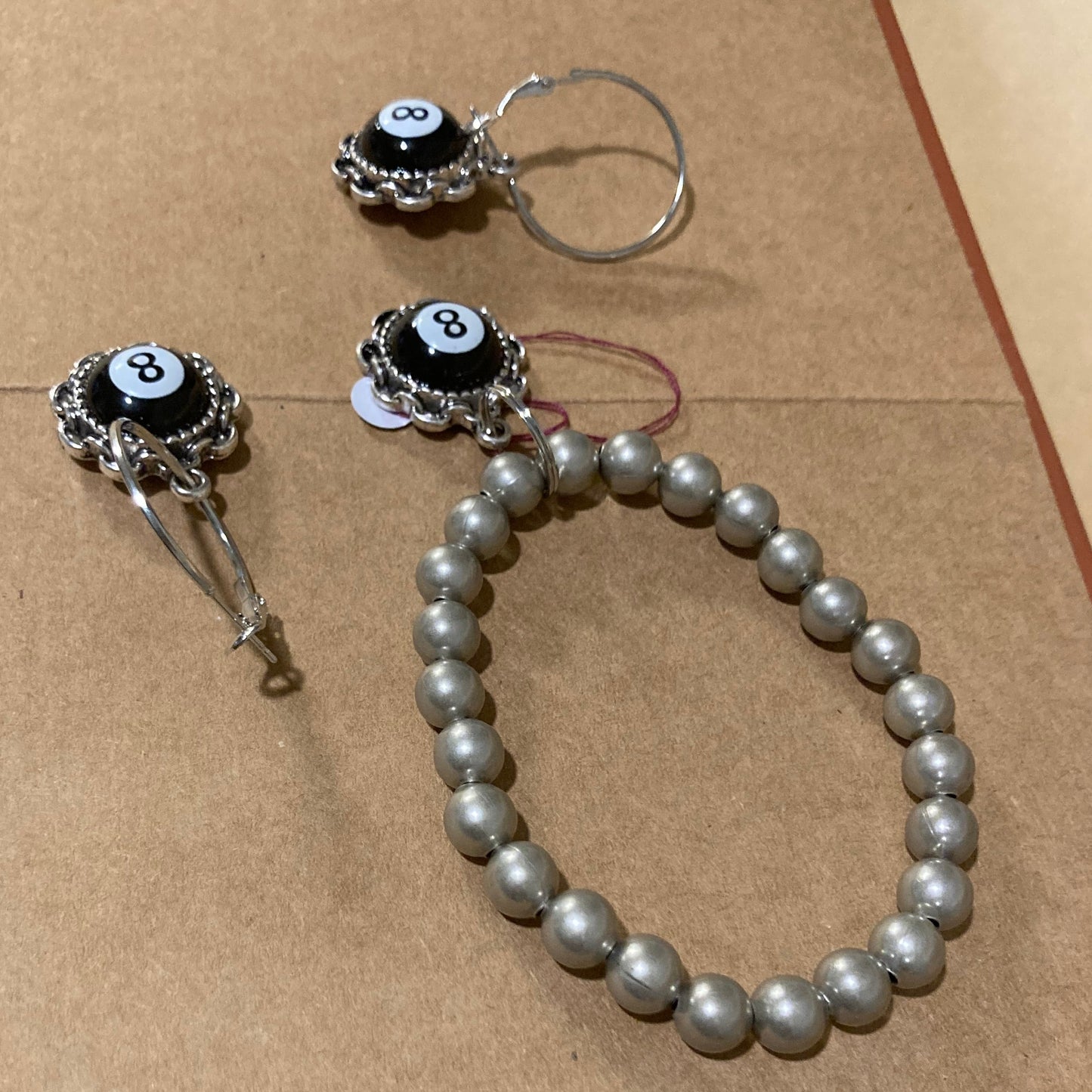 Silver-Plated bracelet and earrings with eye charms on a brown surface