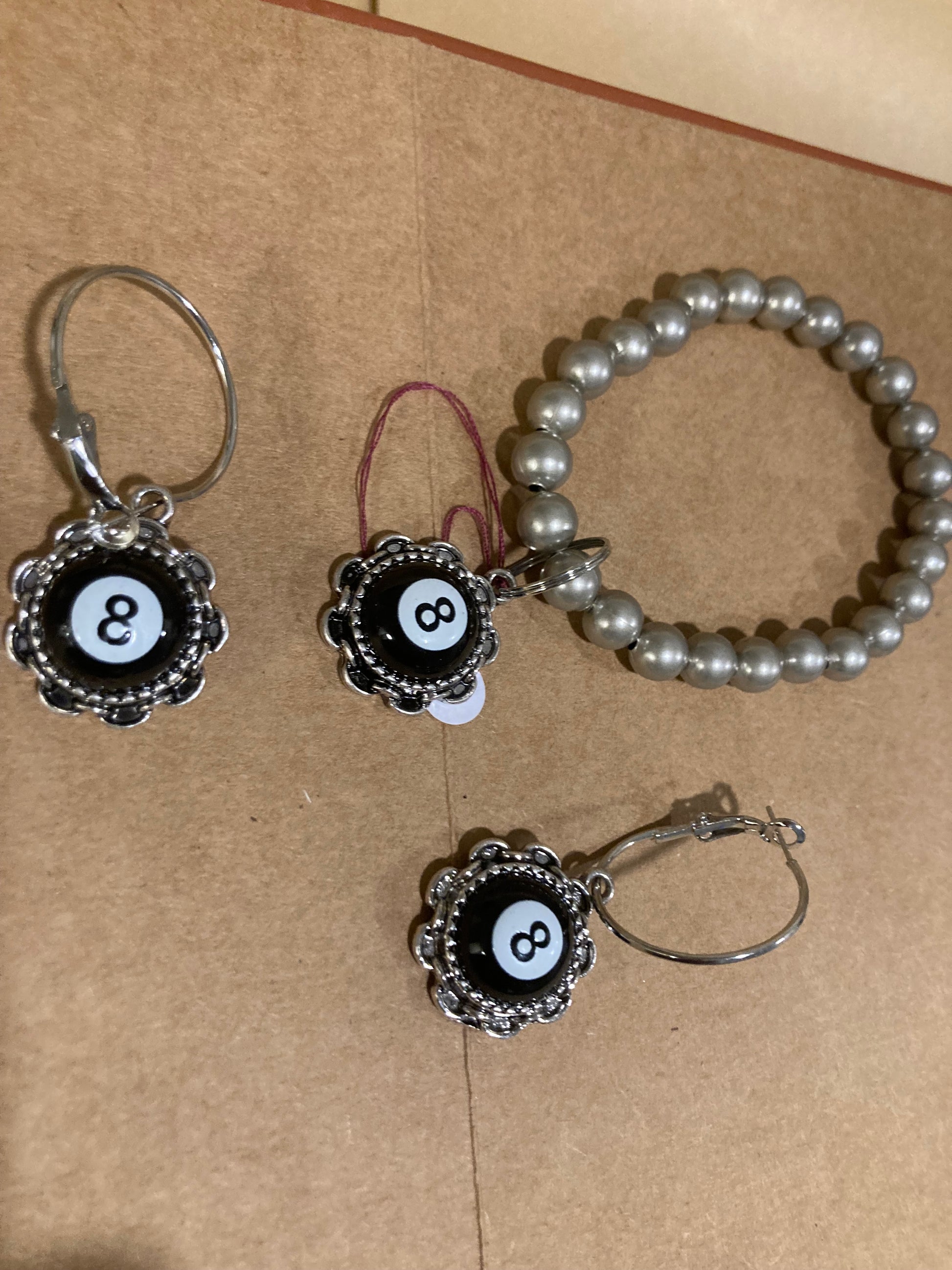 Silver plated bracelet with black and silver earrings on a brown surface