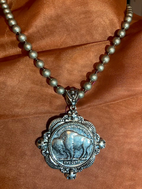 Decorative necklace with a silver pendant on a brown fabric background