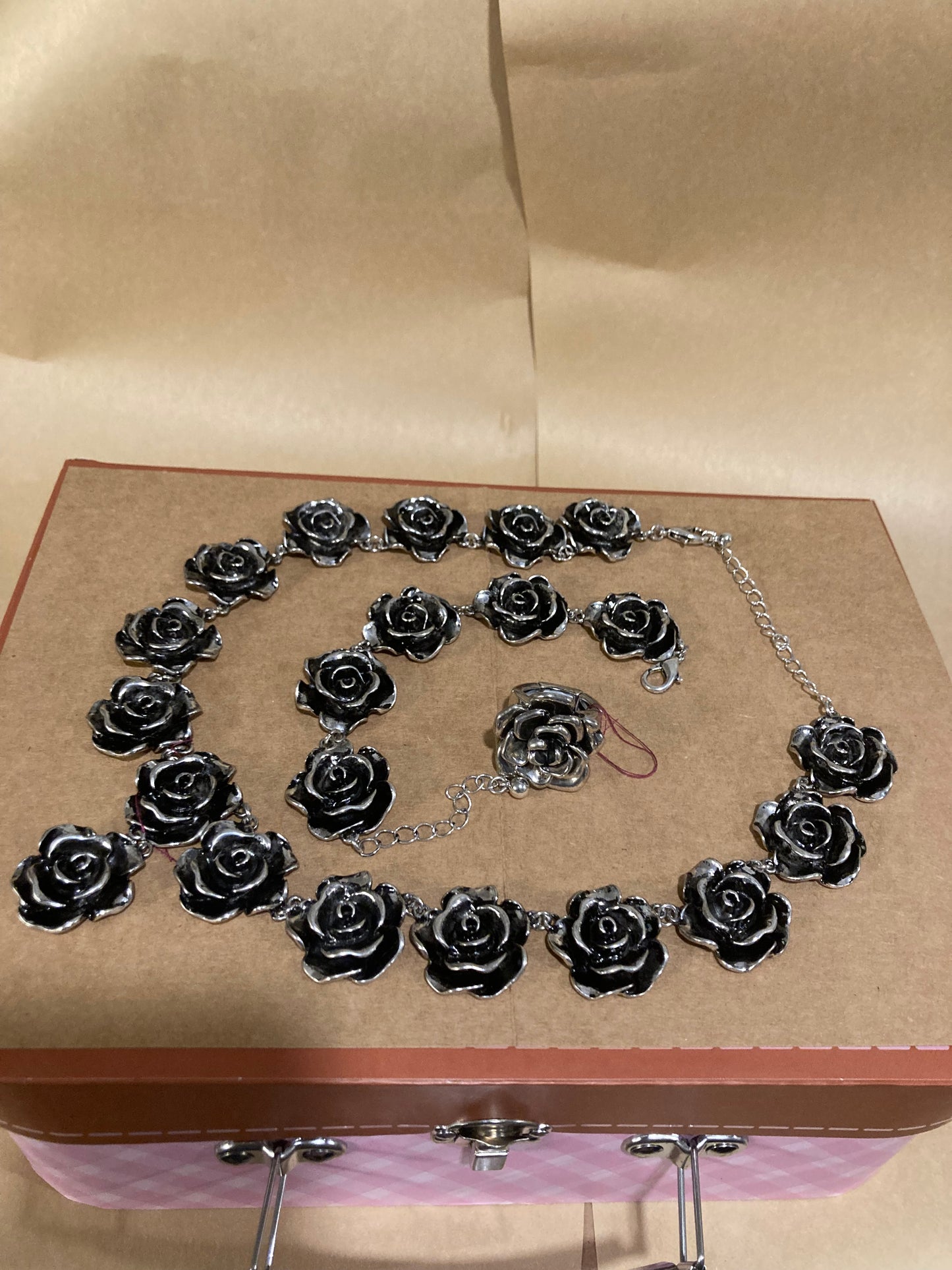 Silver rose necklace and earrings on a cardboard background