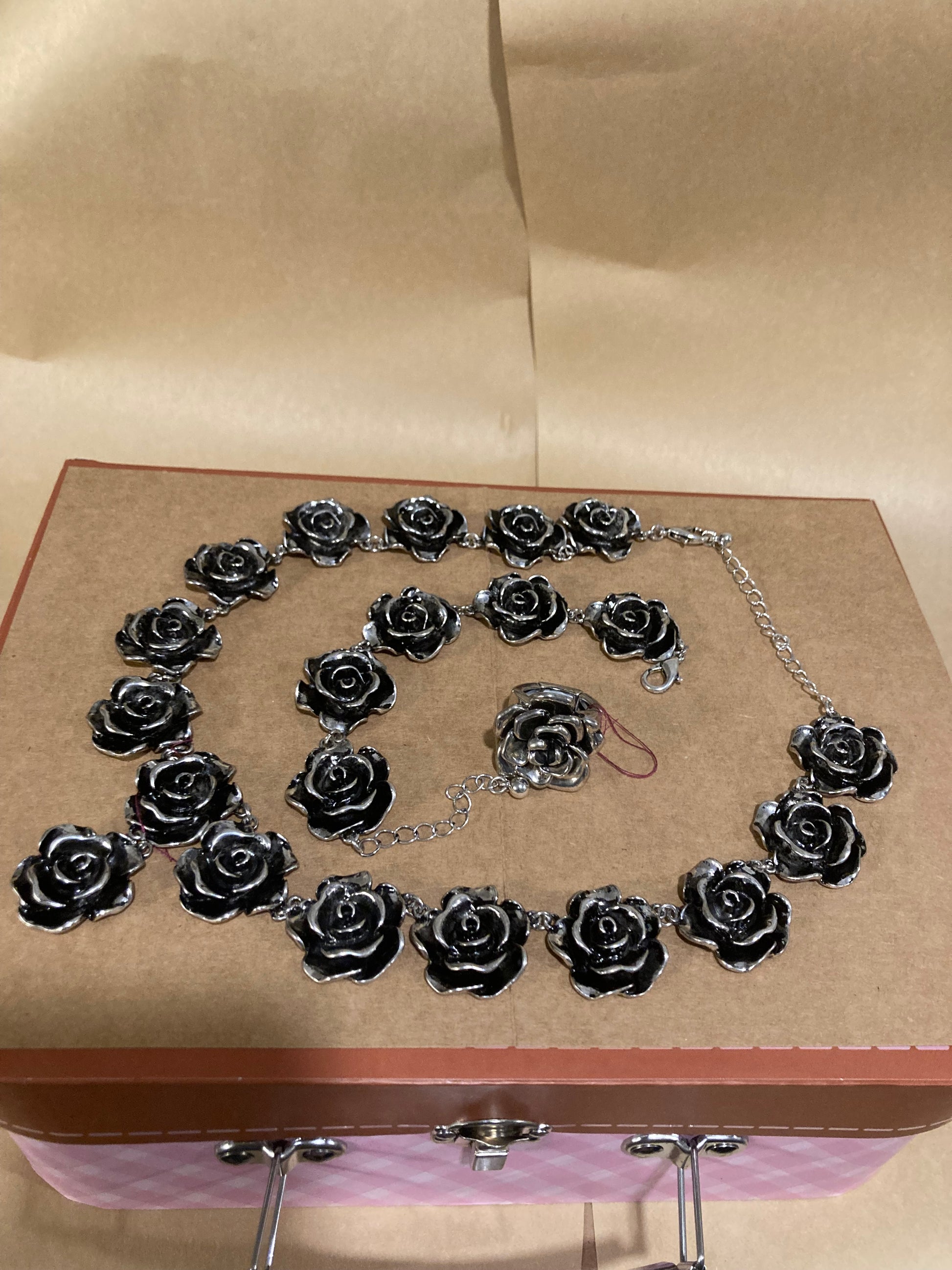 Silver rose necklace and earrings on a cardboard background