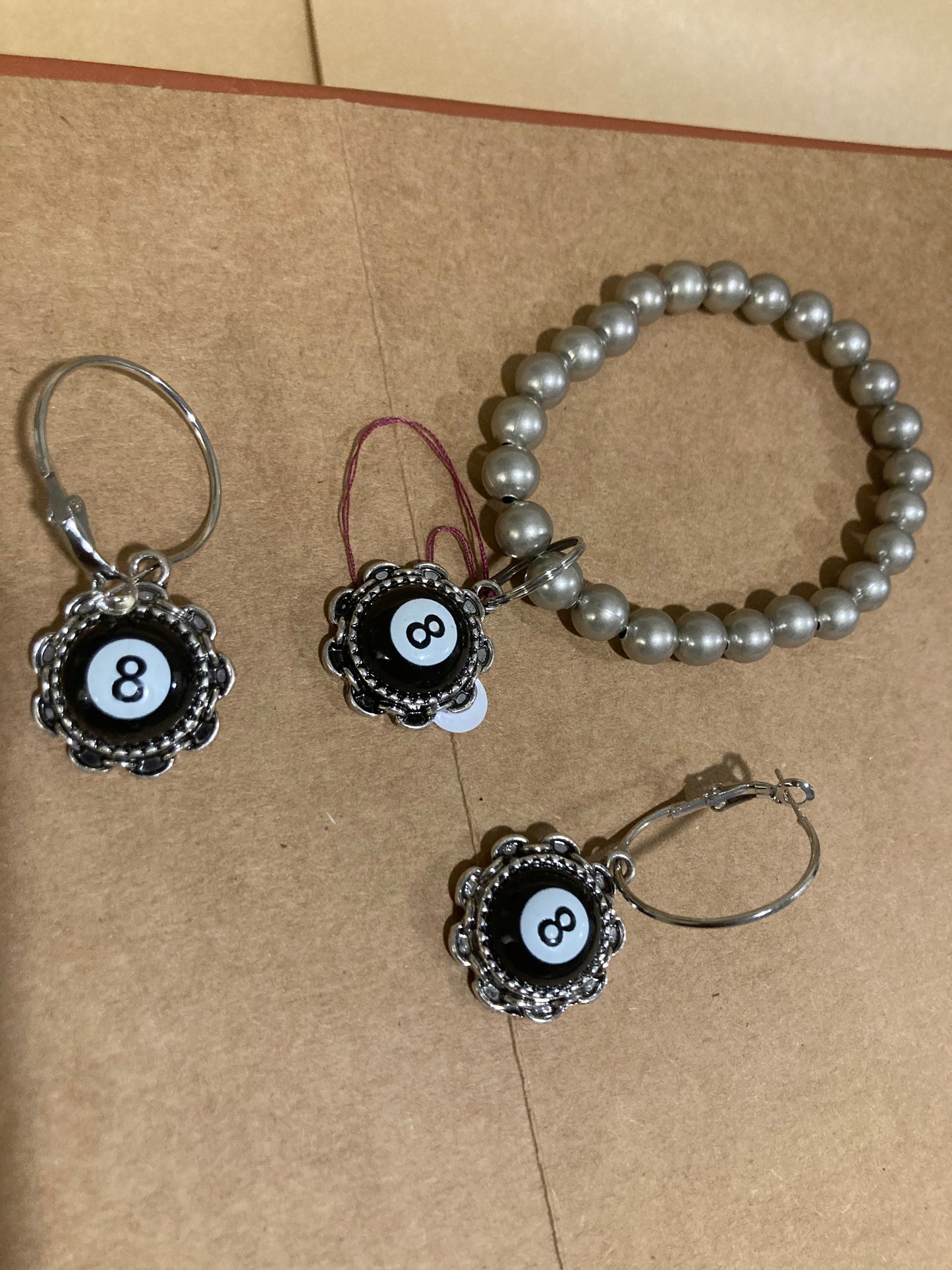 8 Ball bezel bracelet and black and silver earrings on a brown surface