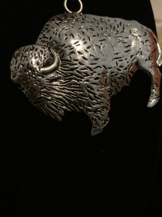 Metallic Buffalo Hand shaped pendant on a black background