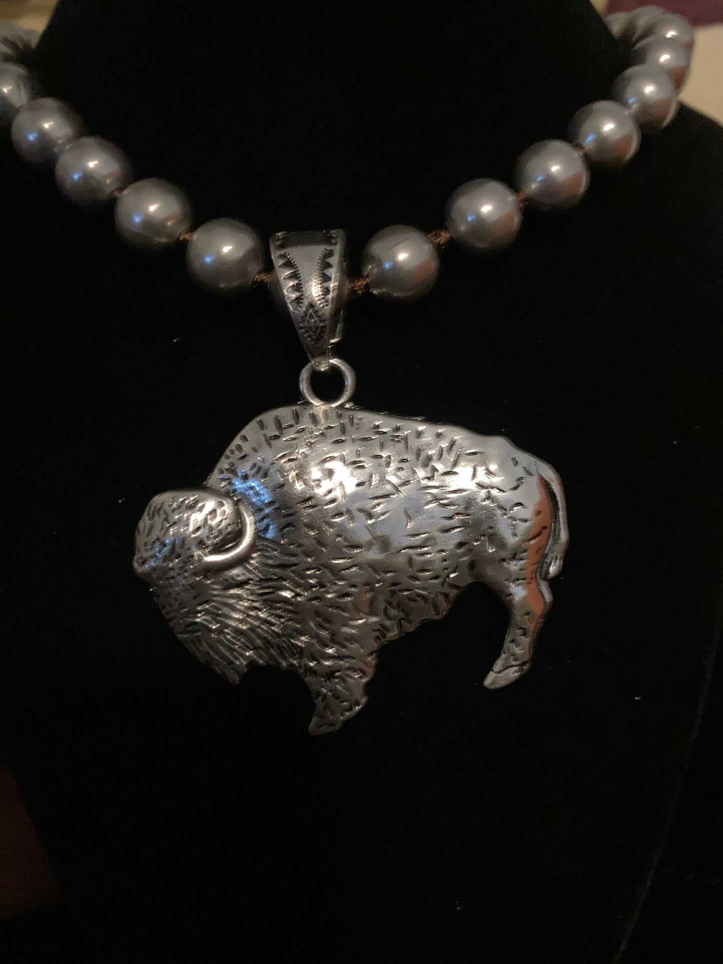 Silver fish-shaped pendant on a necklace against a dark background
