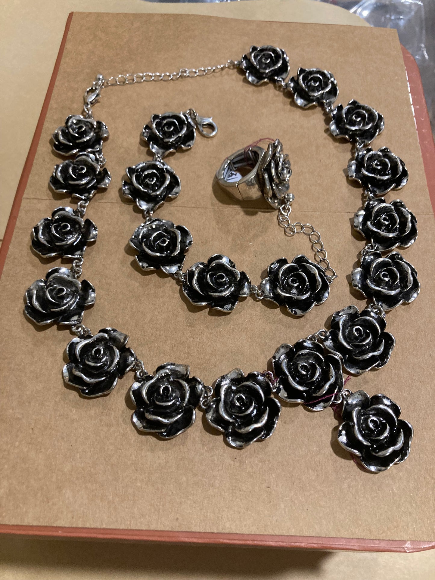 Silver rose-shaped jewelry set on a brown cardboard background