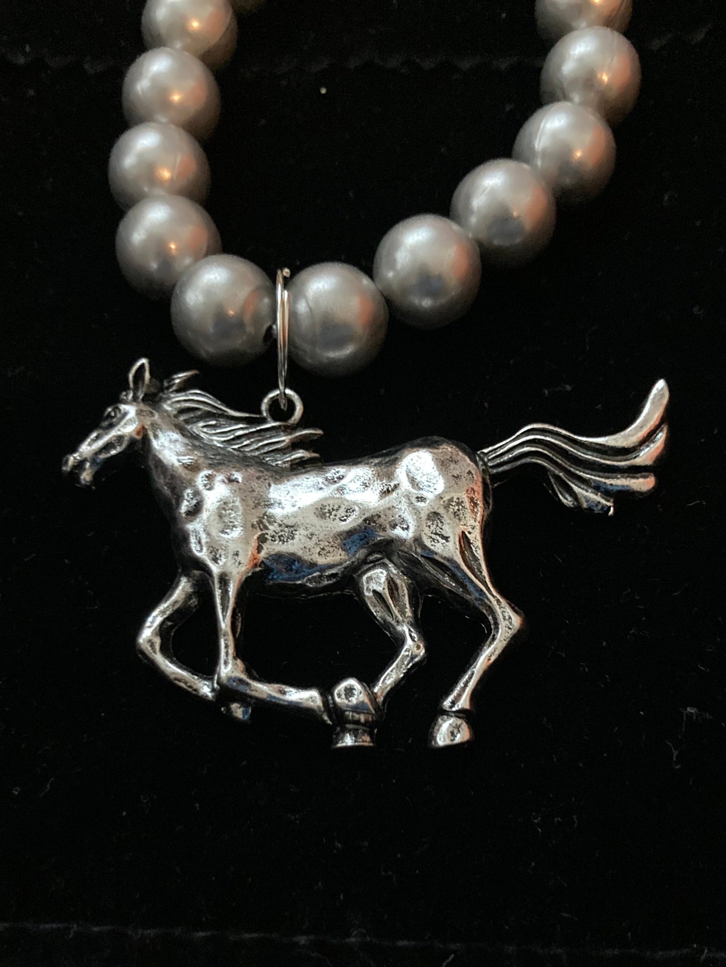 Silver horse brooch on a Beaded Bracelet on dark background