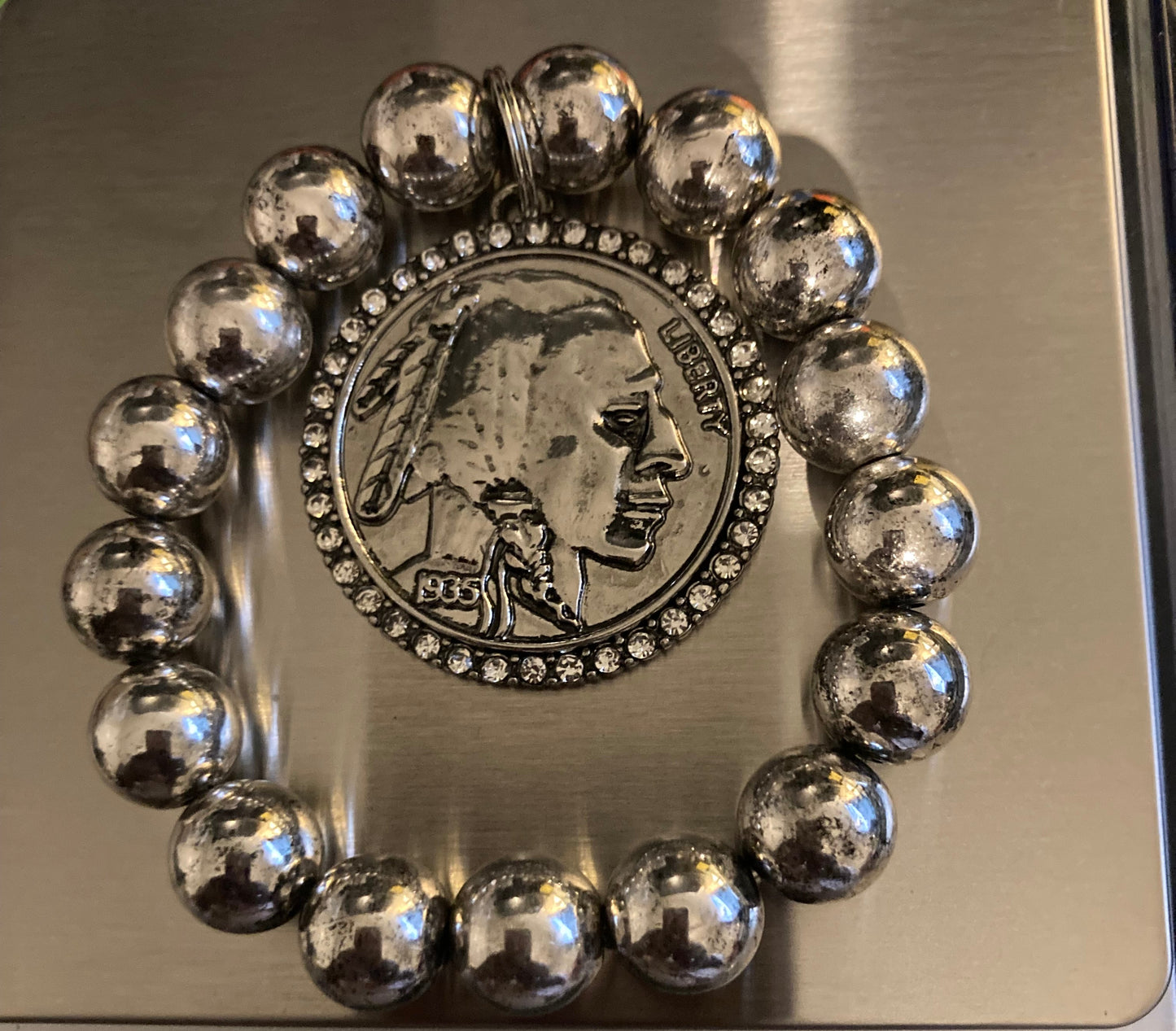 Silver beaded bracelet with a coin charm on a digital scale