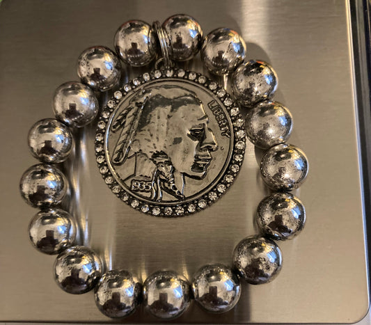 Silver beaded bracelet with a coin charm on a digital scale