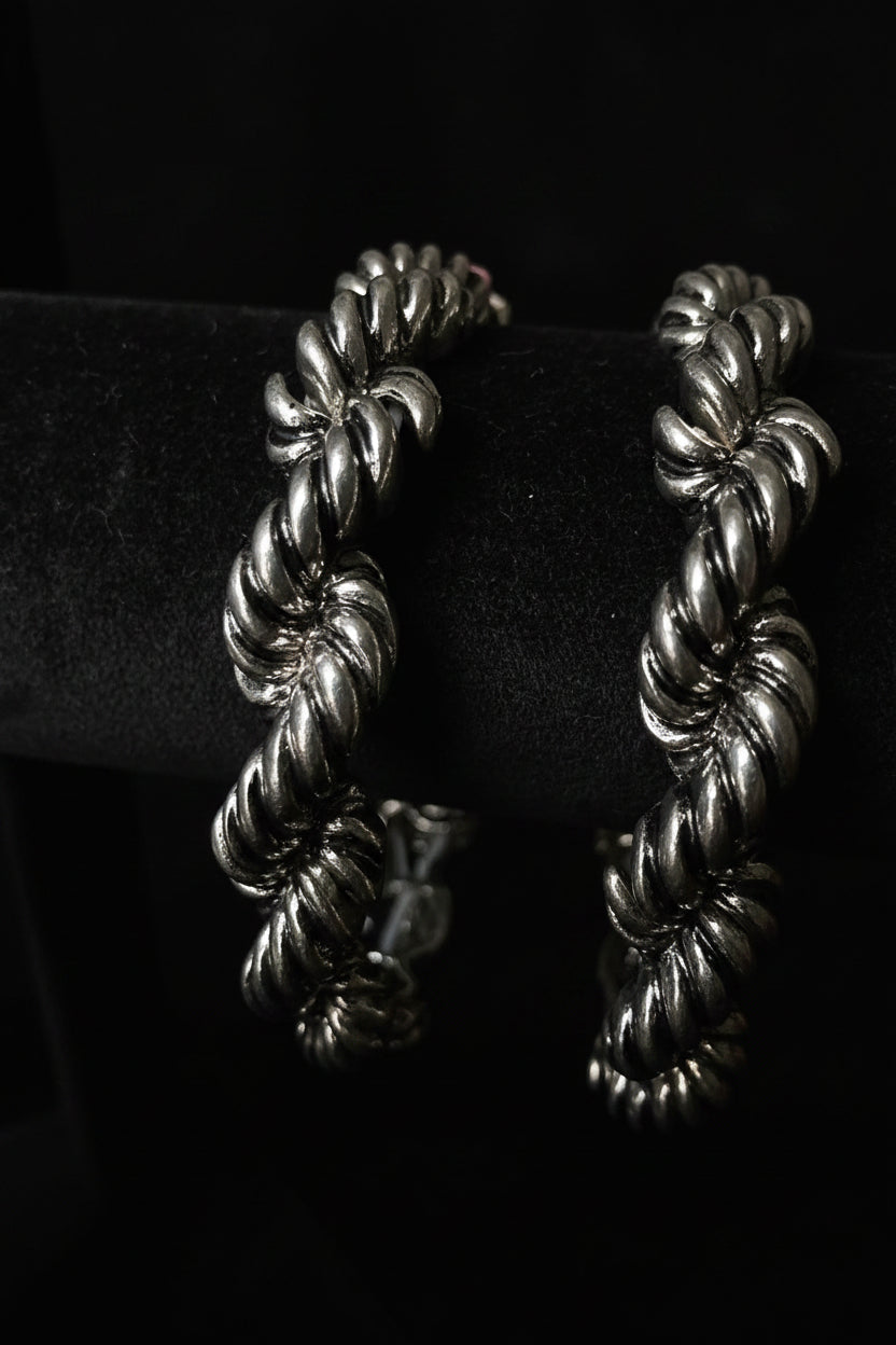 Silver braided bracelet on a black stand with a colorful background
