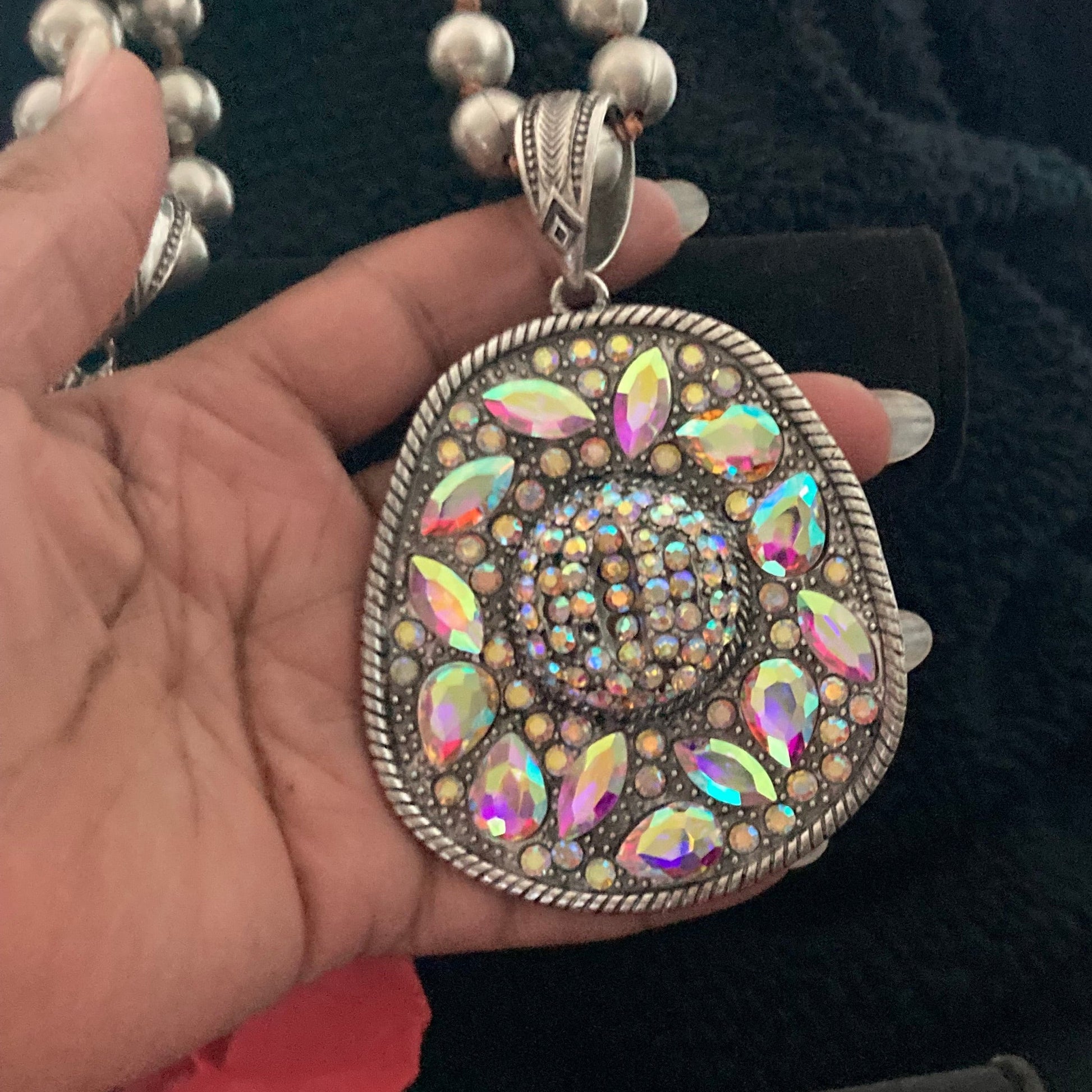 Decorative Cowgirl Hat pendant held by a hand with a black background