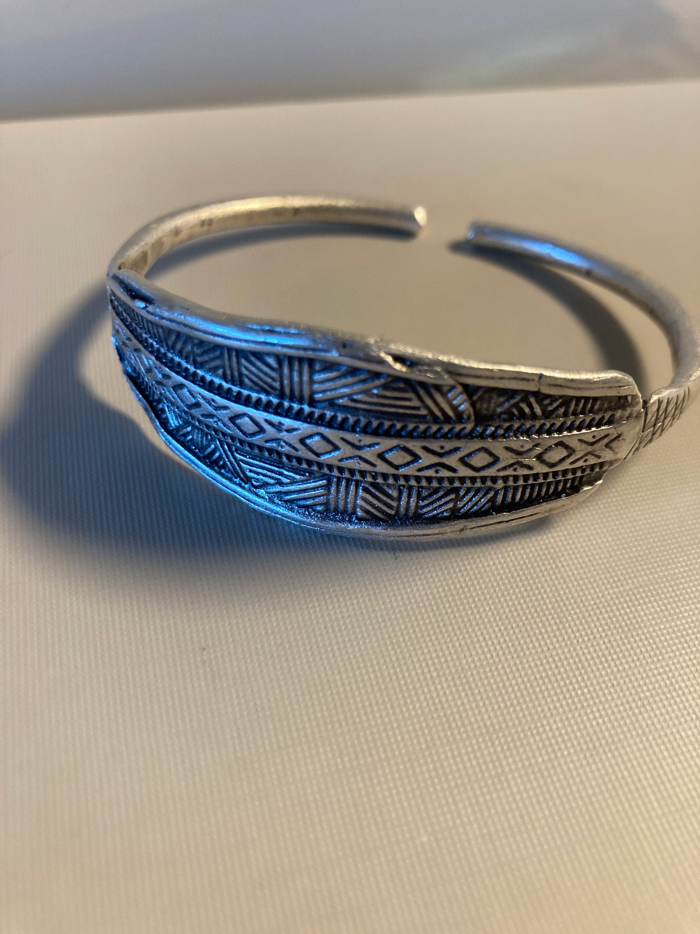 Silver bracelet with intricate patterns on a light fabric background