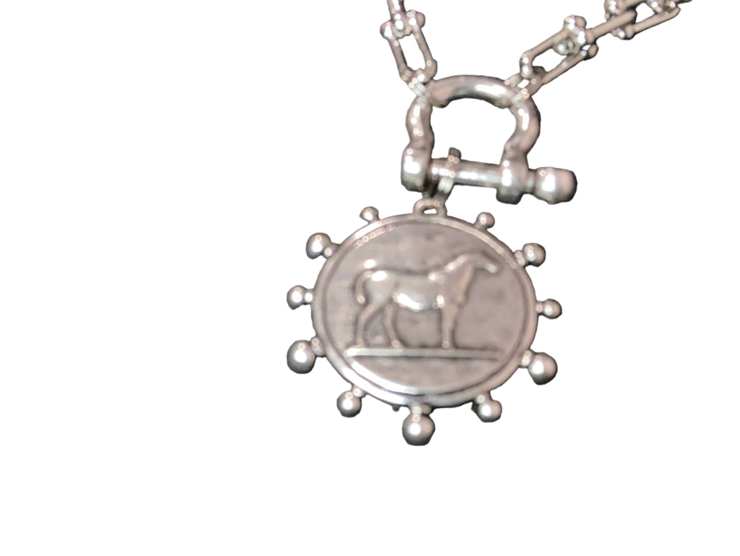 Silver pendant of a horse charm with a detailed clasp on a dark background