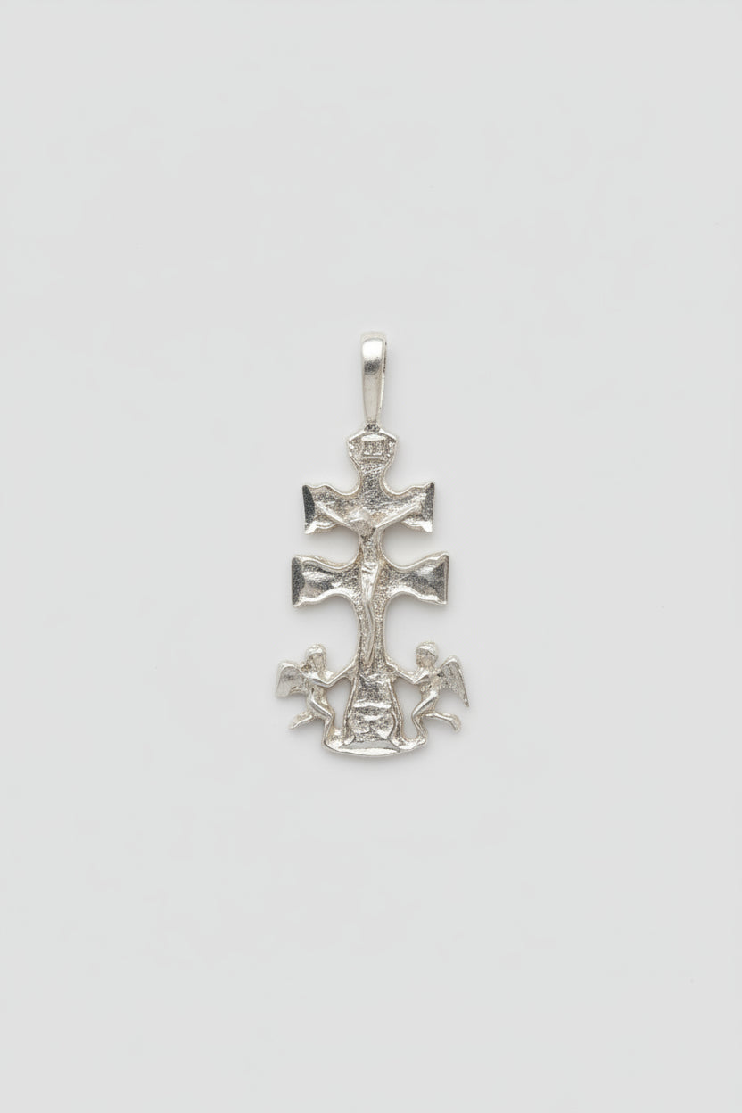 Silver cross pendant/charm on a light background
