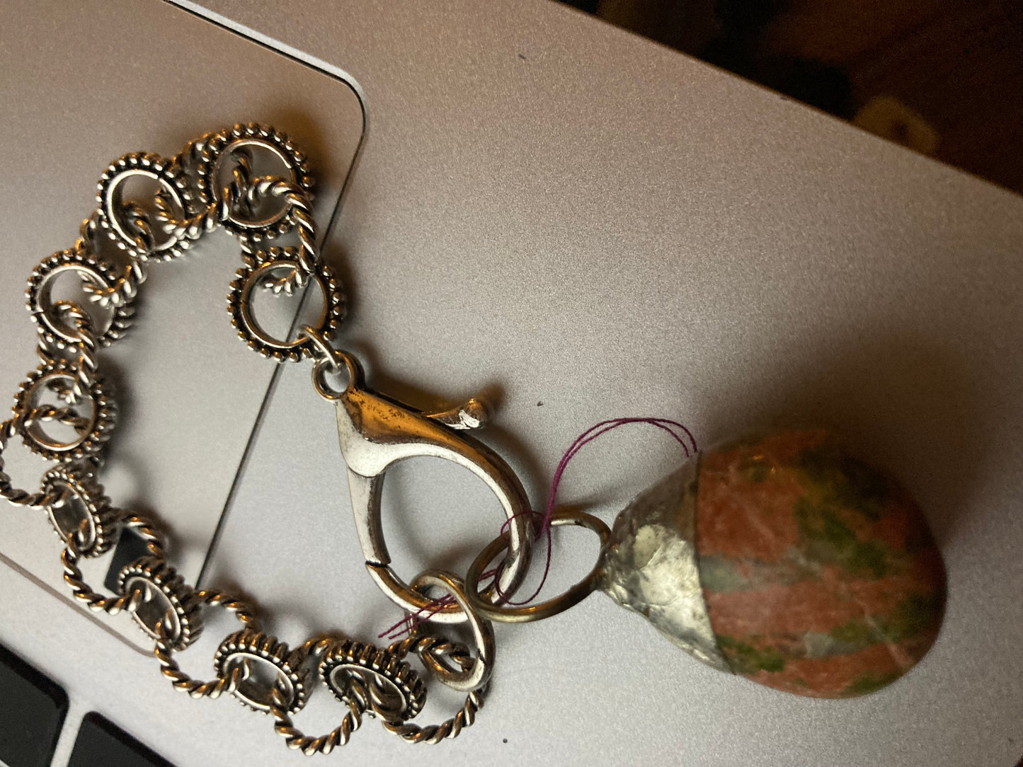 Brass chain with a clasp and Palm stone on a light surface