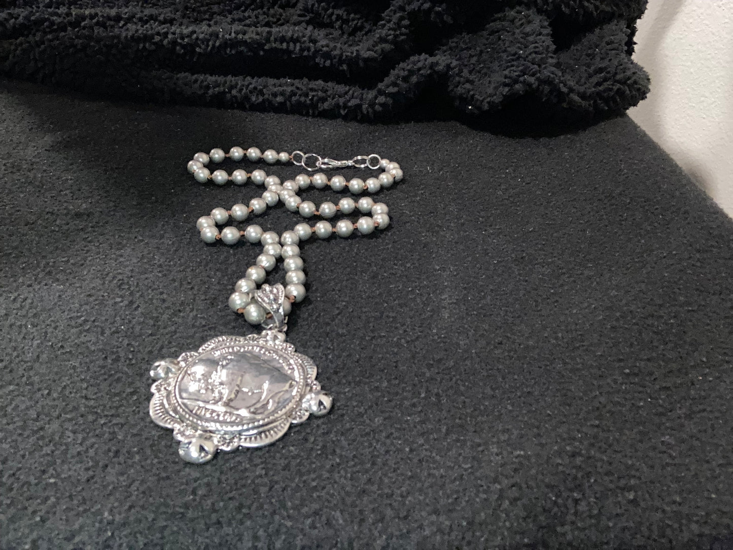 Silver plated necklace with 
bison Pendant and decorative clasp on a dark background
