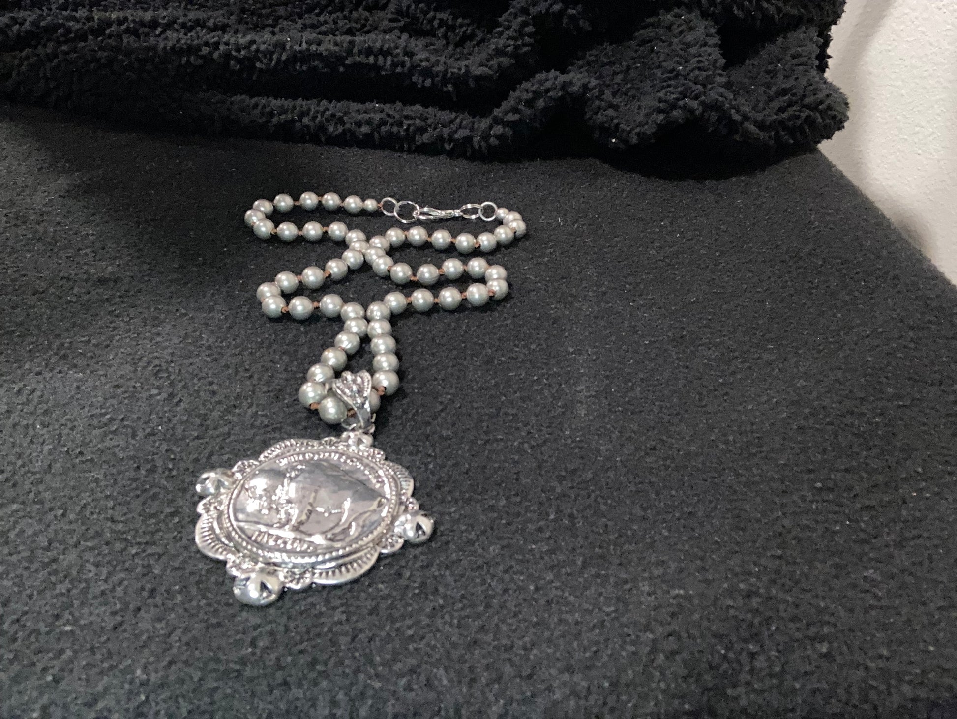 Silver plated necklace with 
bison Pendant and decorative clasp on a dark background