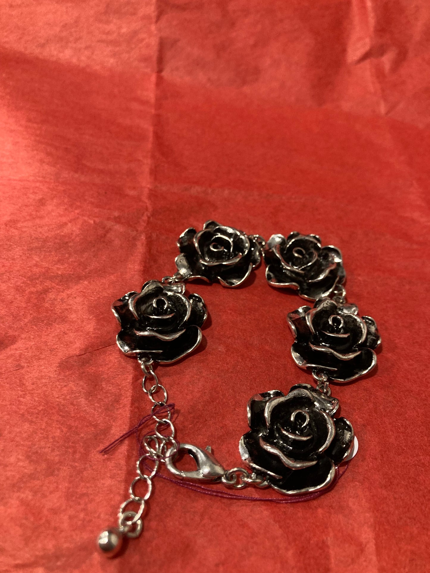 Silver rose bracelet on a red textured background
