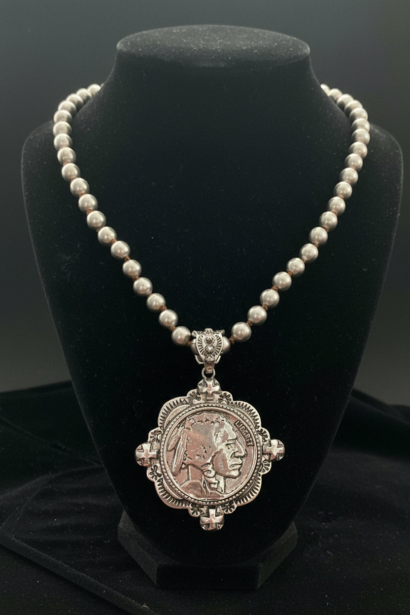 Silver necklace with a detailed pendant on a black stand