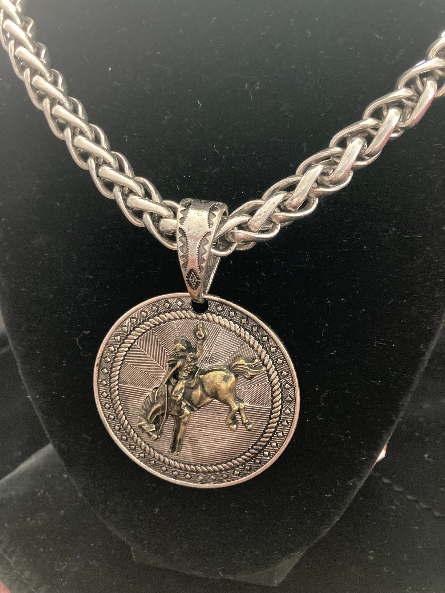 Silver chain necklace with a round pendant featuring a horse and rider on a black background
