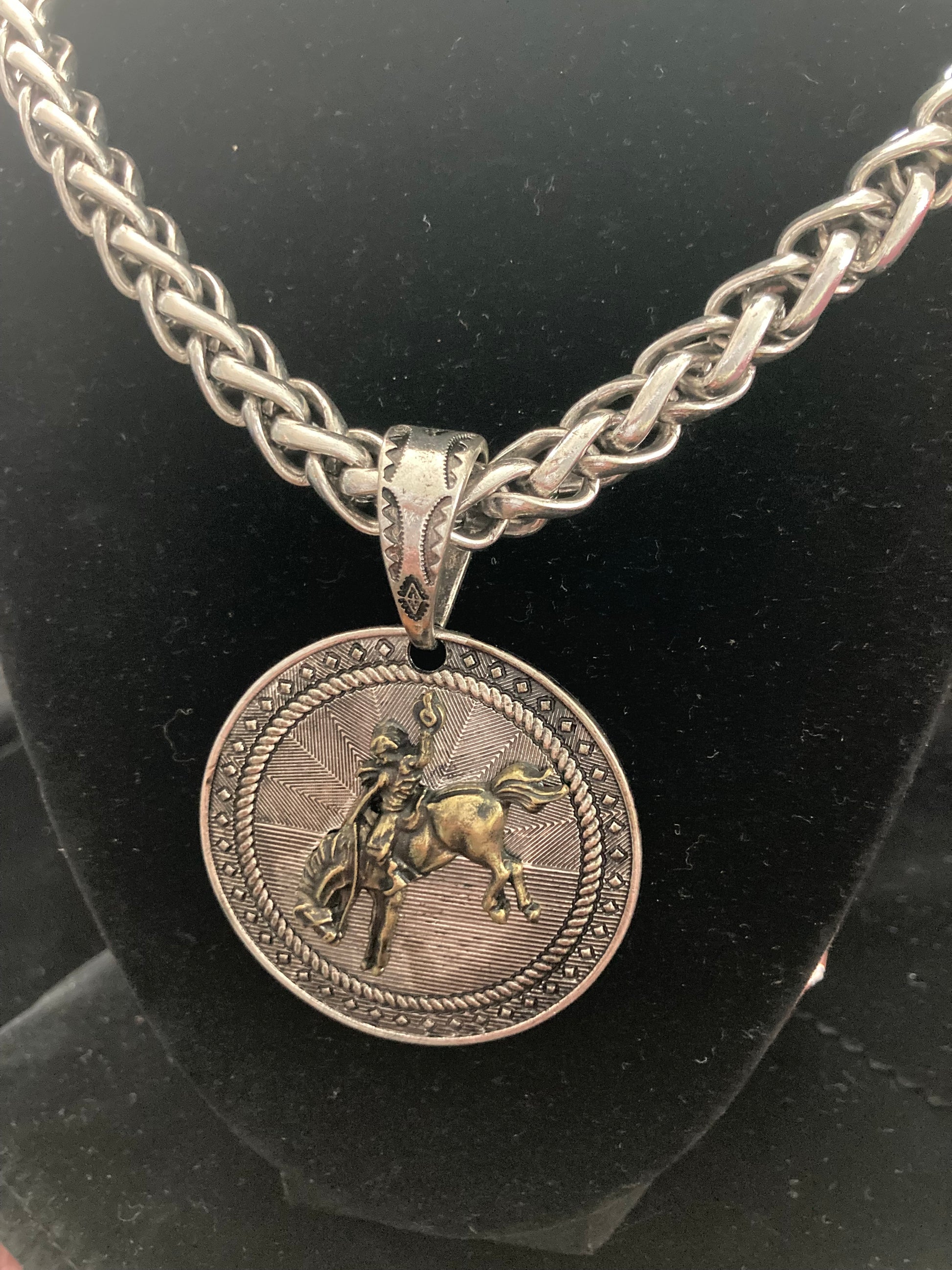 Silver chain necklace with a round pendant featuring a horse and rider on a black background