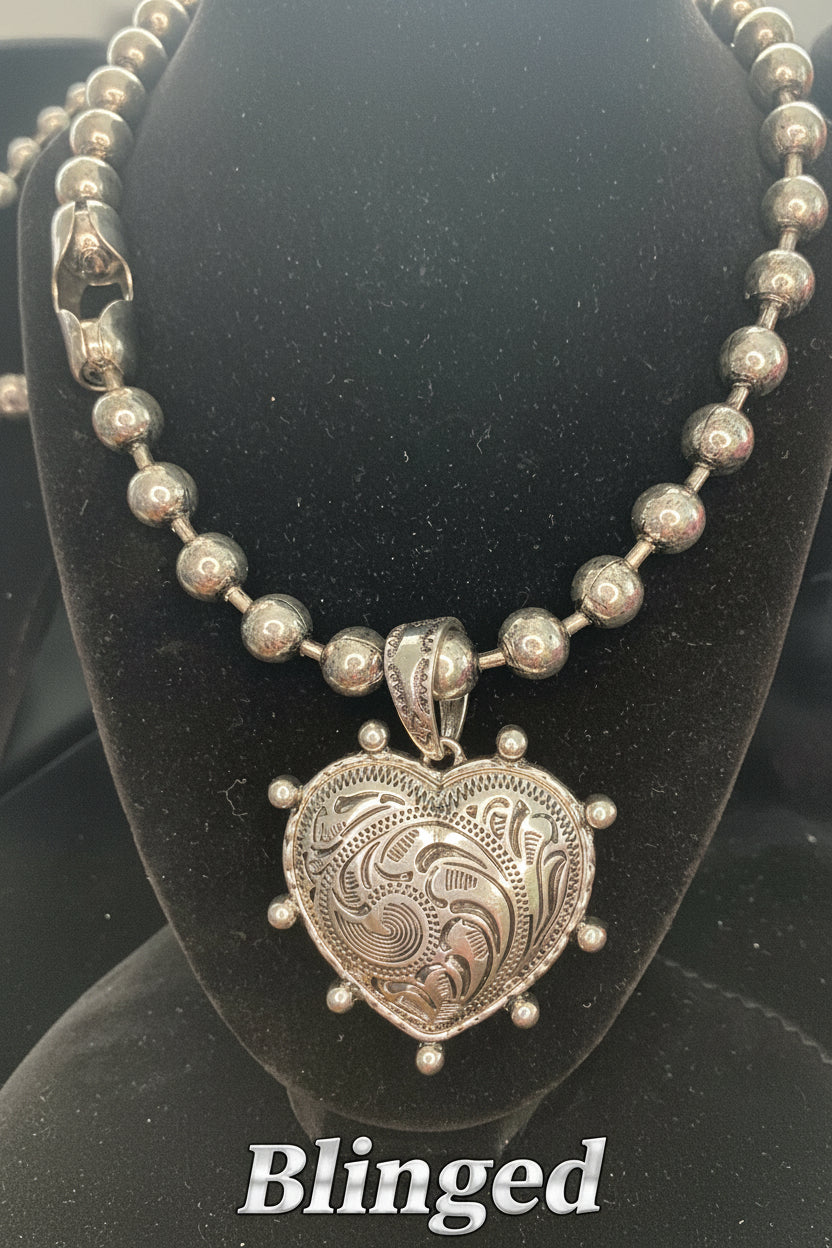 Silver necklace with a heart-shaped Medallion on a black stand