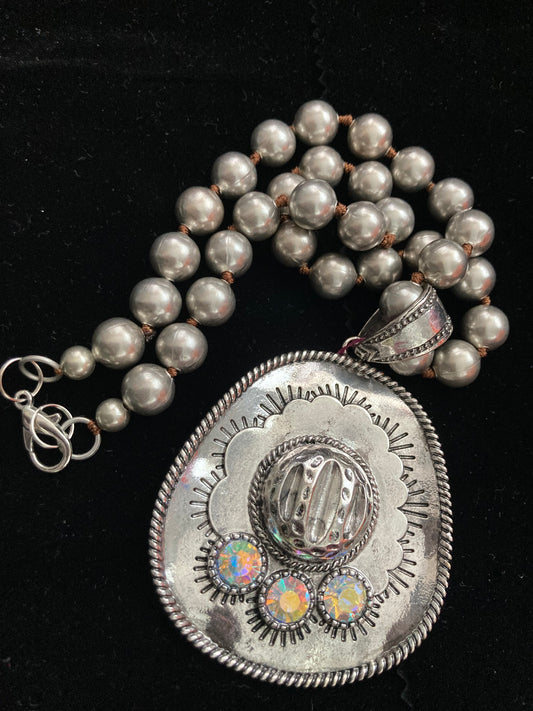 Necklace with silver beads and decorative silver pendant on a black background