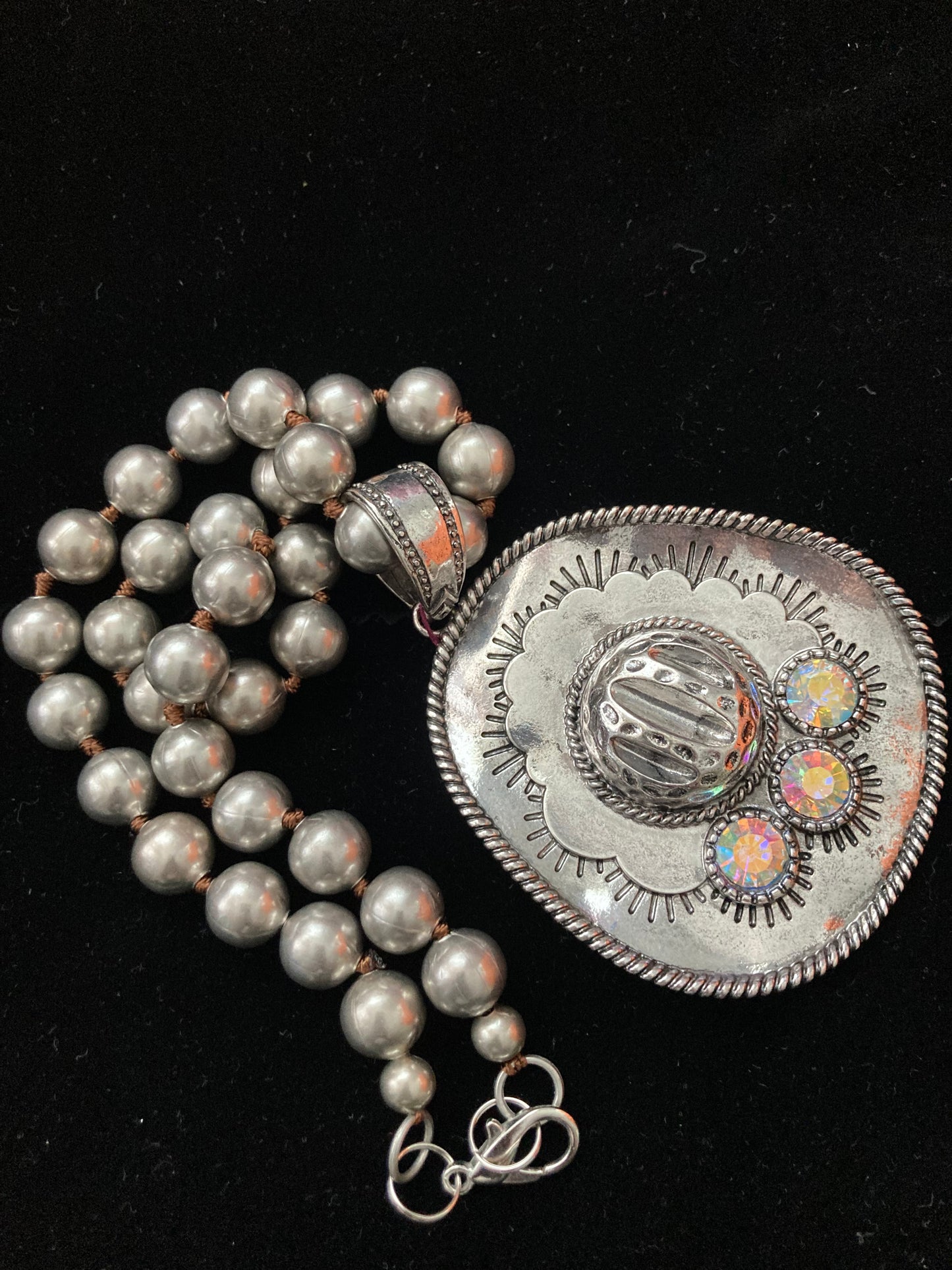 Silver necklace with a decorative clasp on a black background