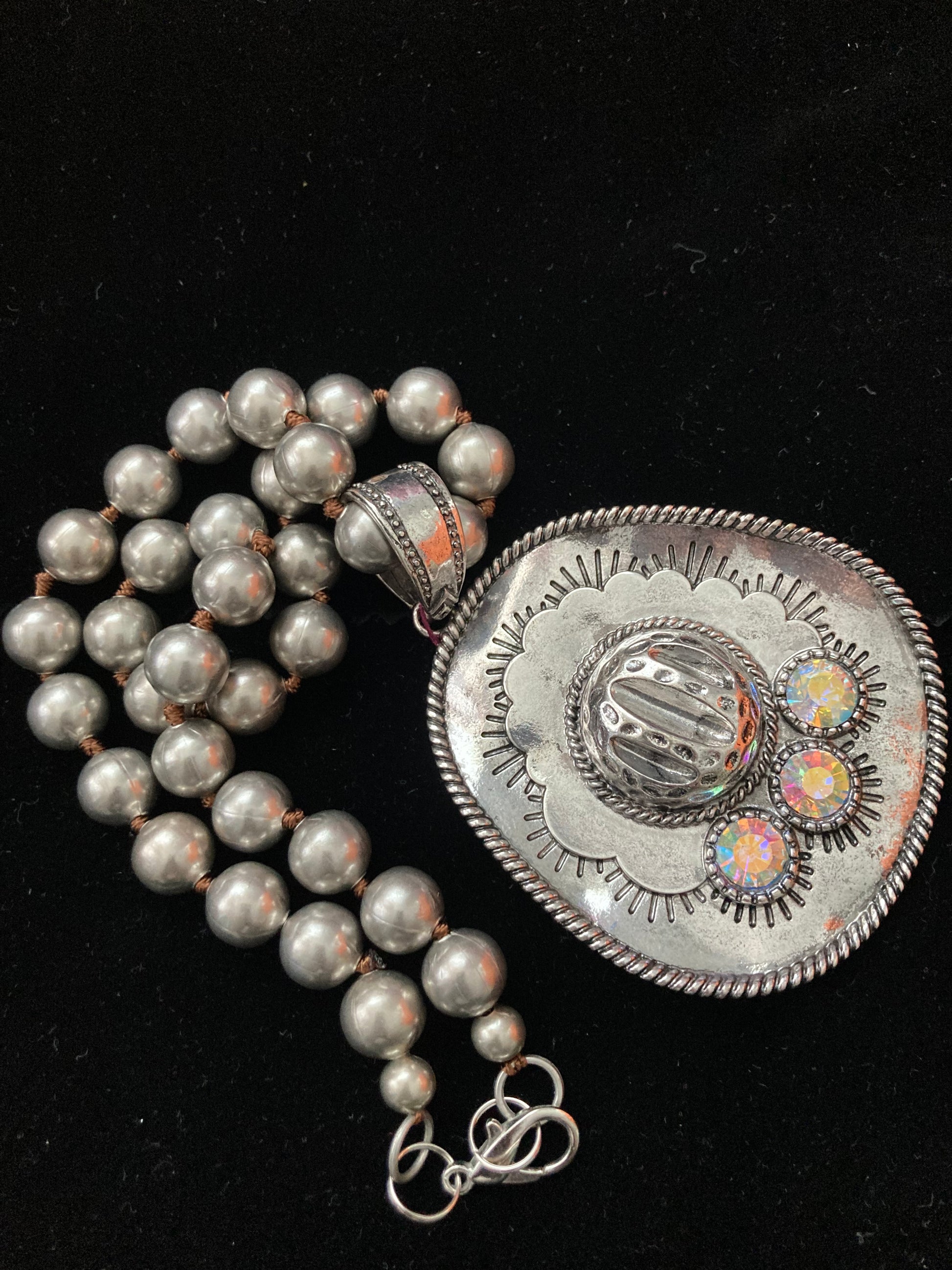 Silver necklace with a decorative clasp on a black background