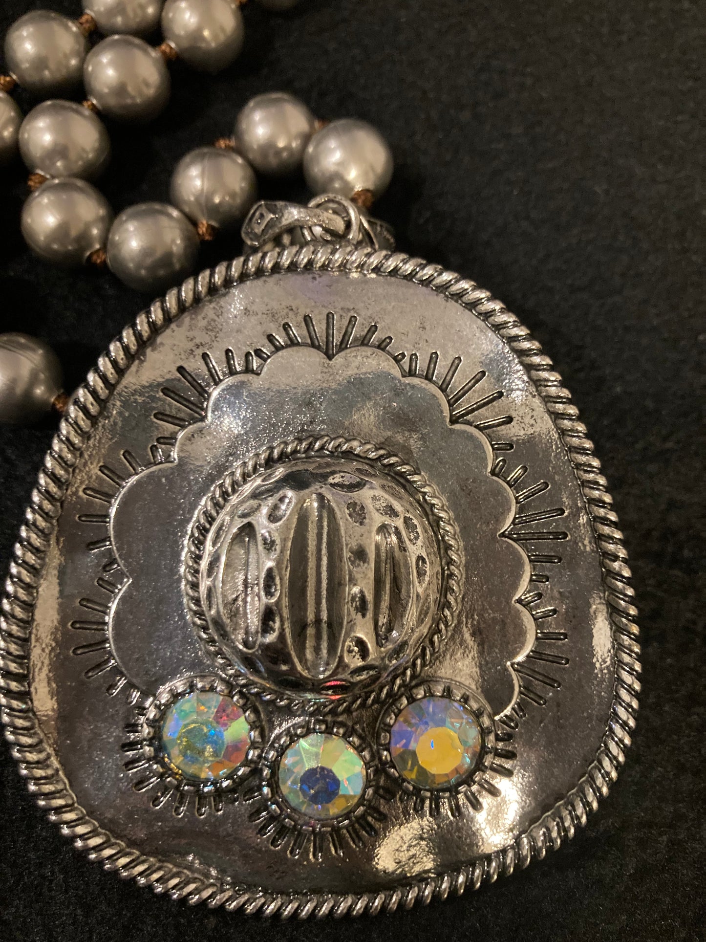 Close-up of a silver plated concho with embedded stones on a dark background