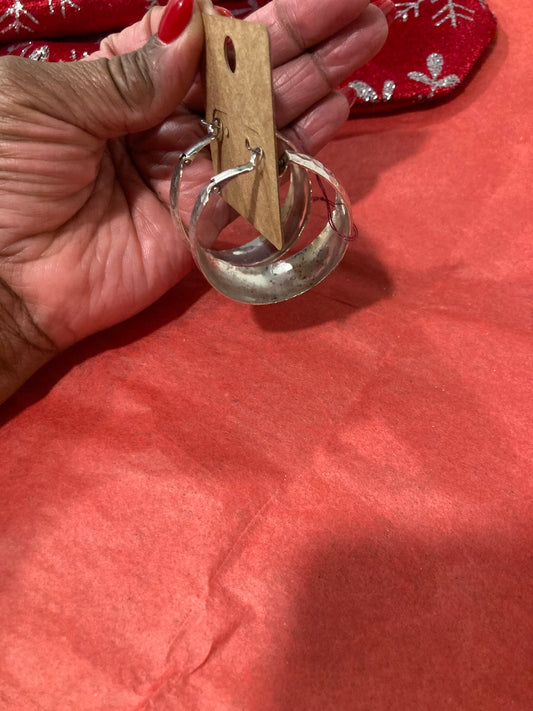 Hand holding a Silver-Plated Hoop Earrings against a red fabric background