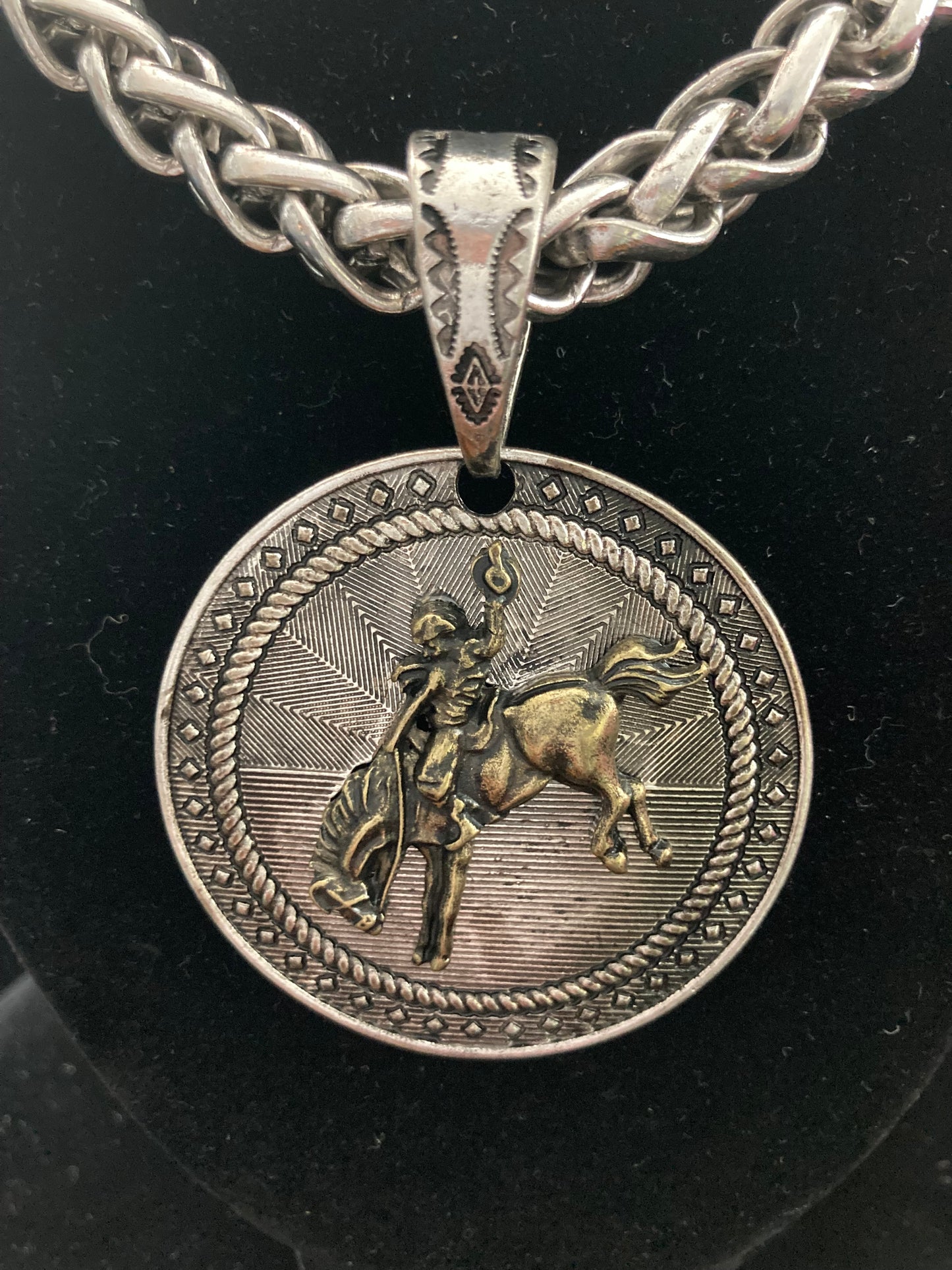 Silver necklace with a round pendant featuring a gold like figure on a black background