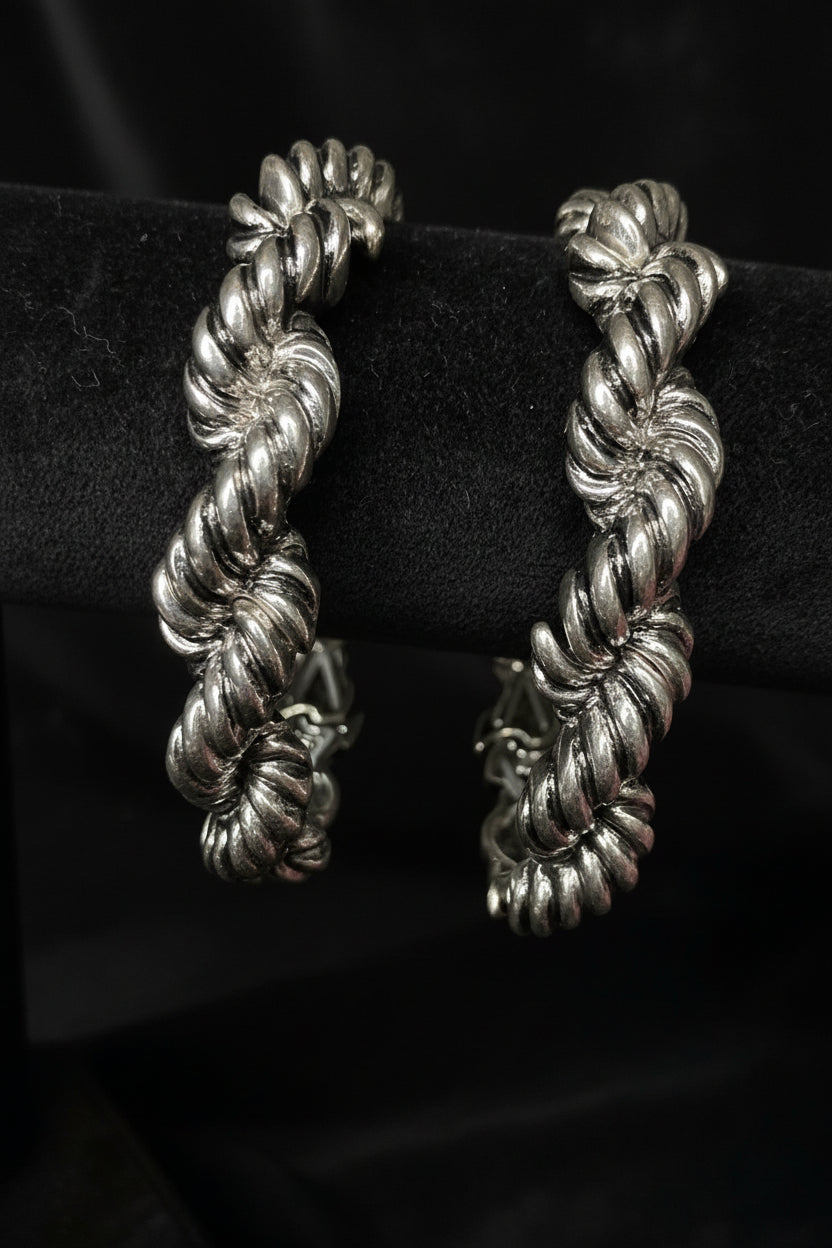 Silver braided Bracelet on a black stand with a floral background