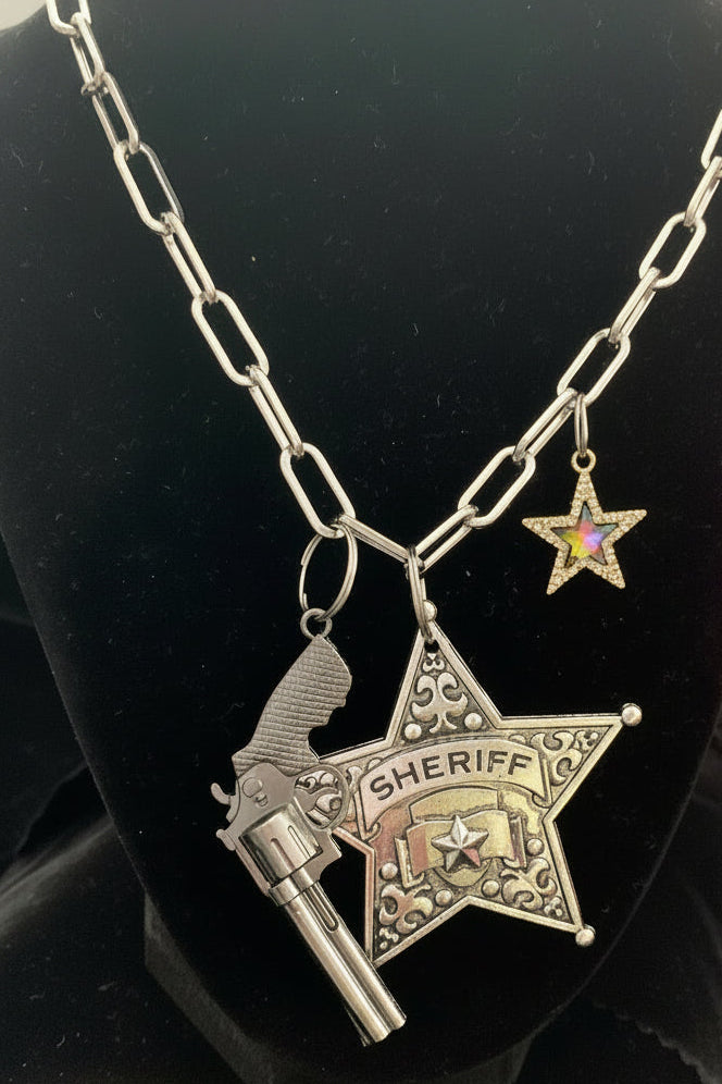 Silver sheriff's star badge with gun charm on a black background