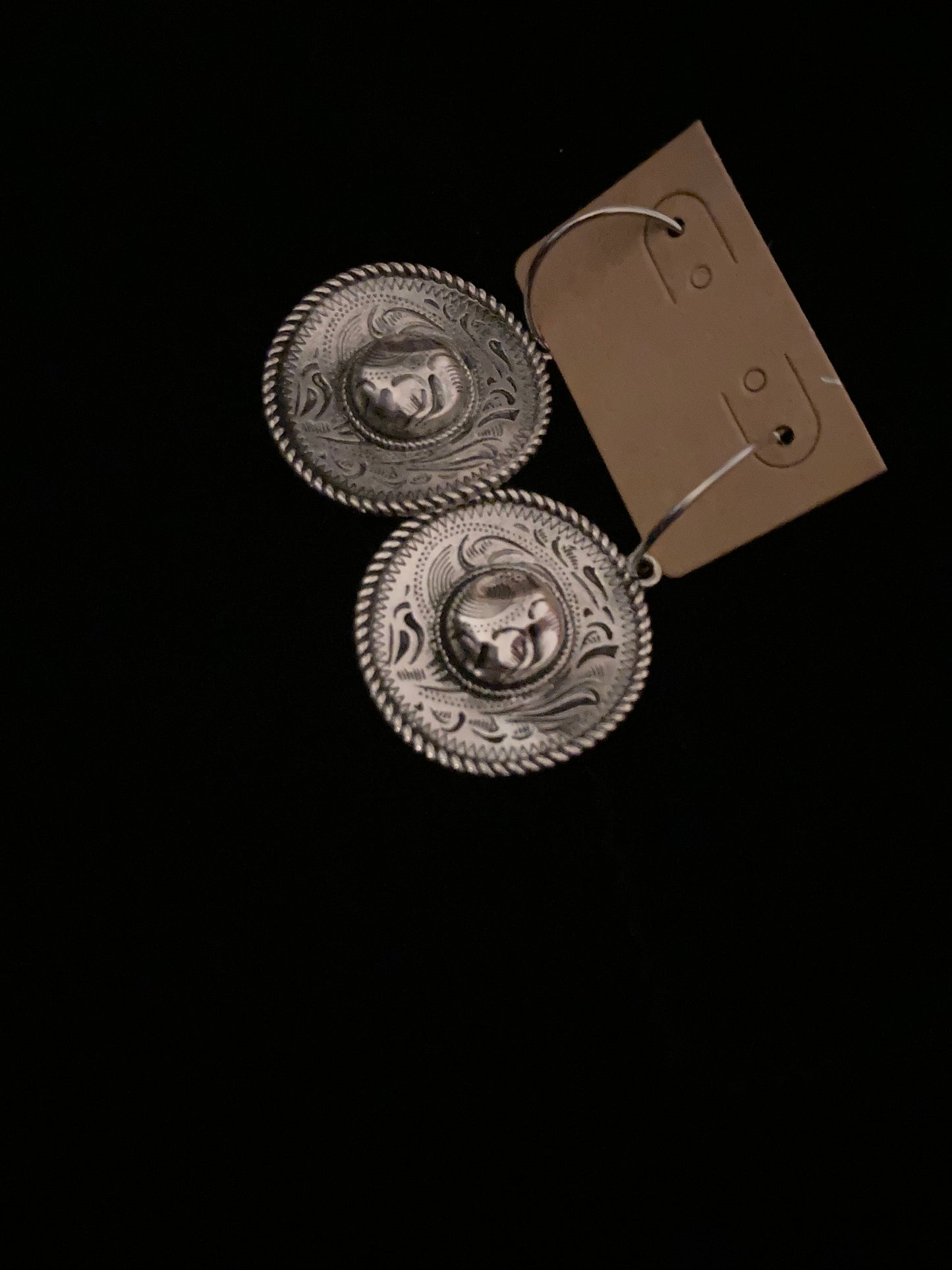 Pair of silver earrings with etched designs on a black background