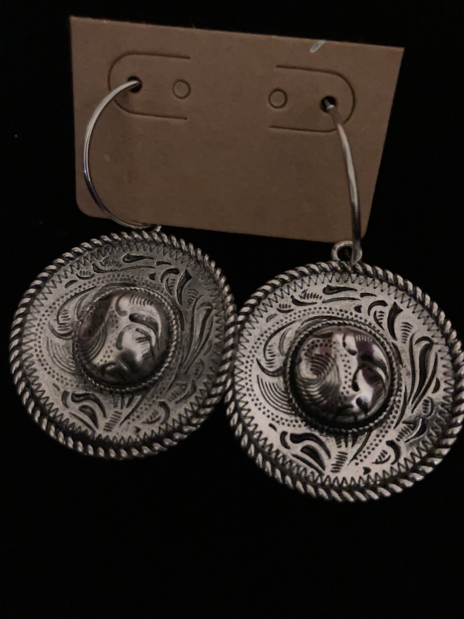 Pair of silver earrings with intricate designs on a black background