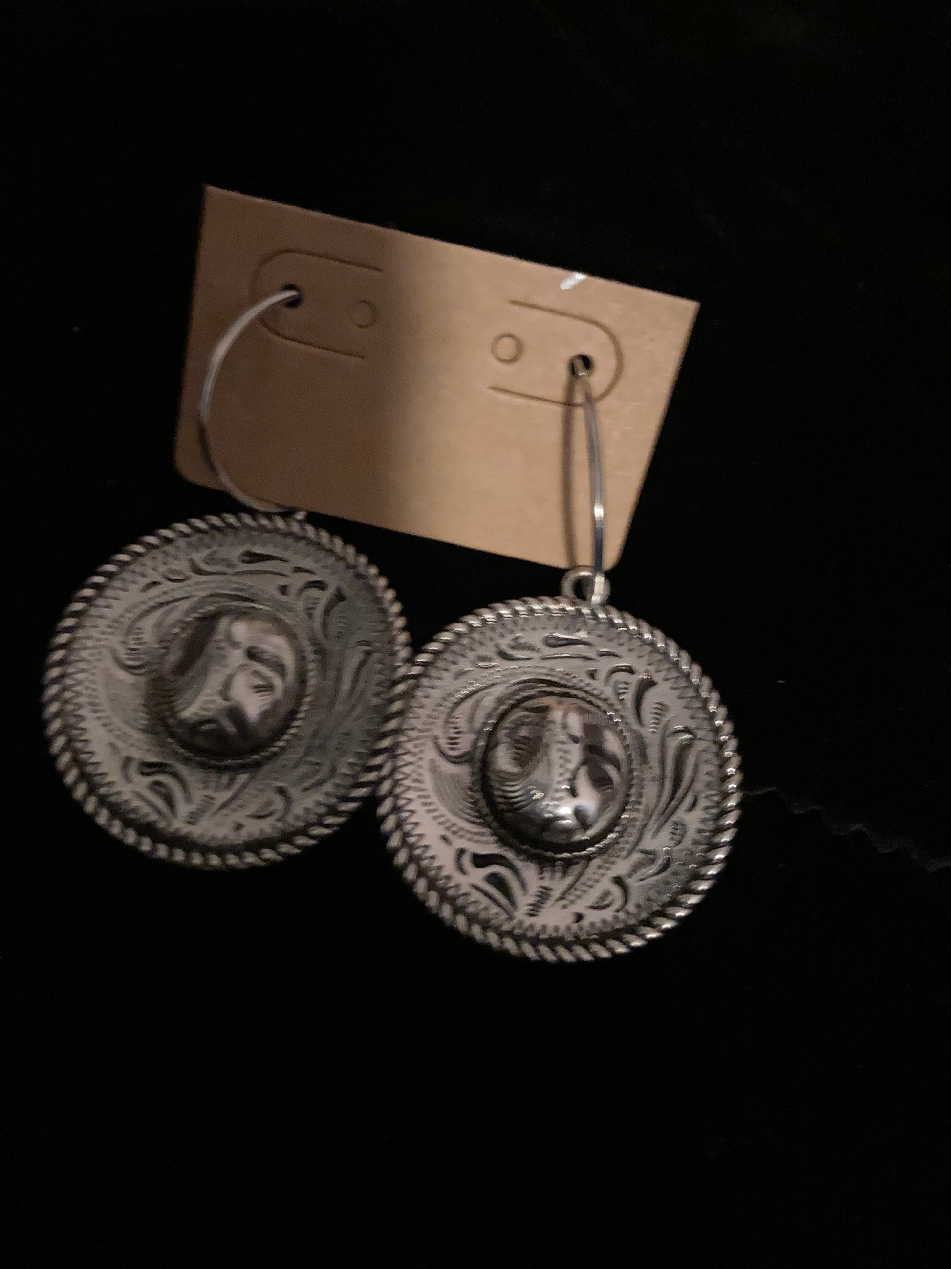 Pair of silver earrings with intricate designs on a black background