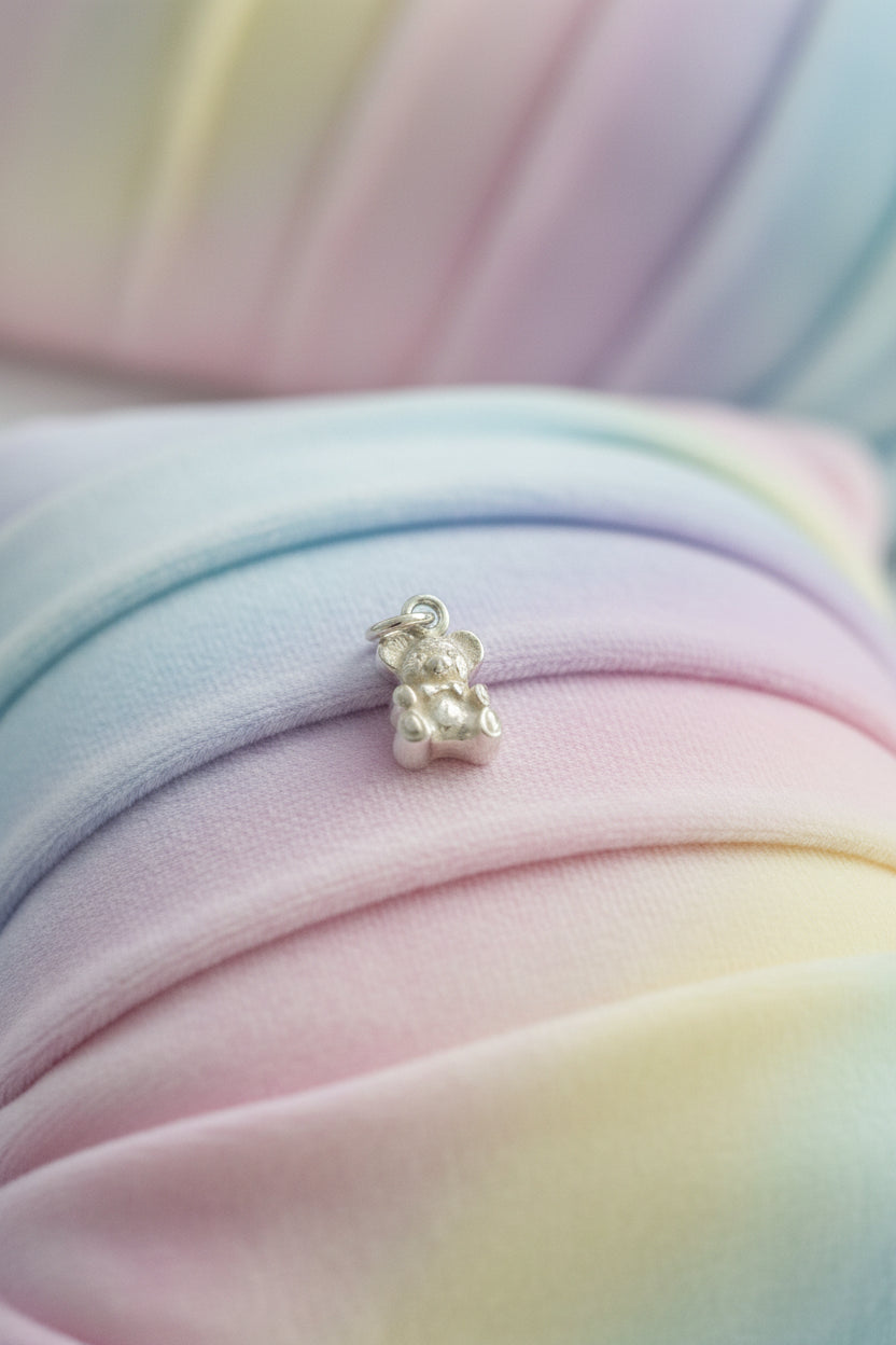 Small silver teddy bear charm on a light background