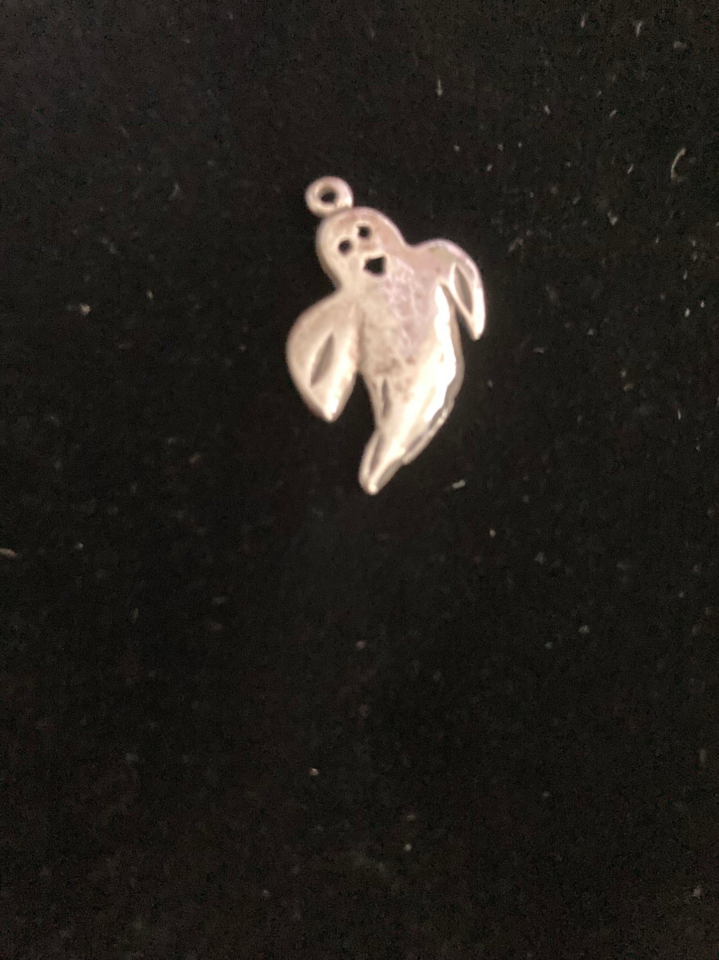 Silver ghost charm on a black background