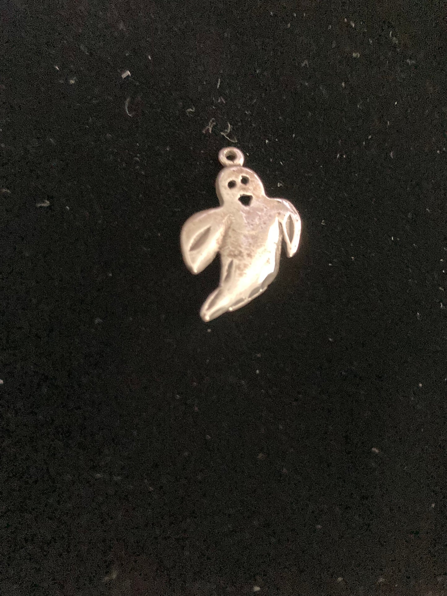 Silver ghost-shaped pendant on a black background