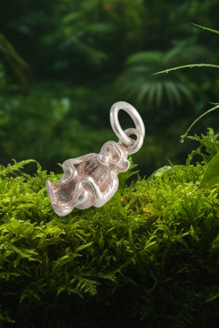 Small silver charm shaped like a Monkey on a black background
