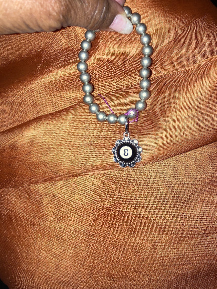 8 Ball chunky charm silver-plated bracelet with a decorative clasp on a brown fabric background
