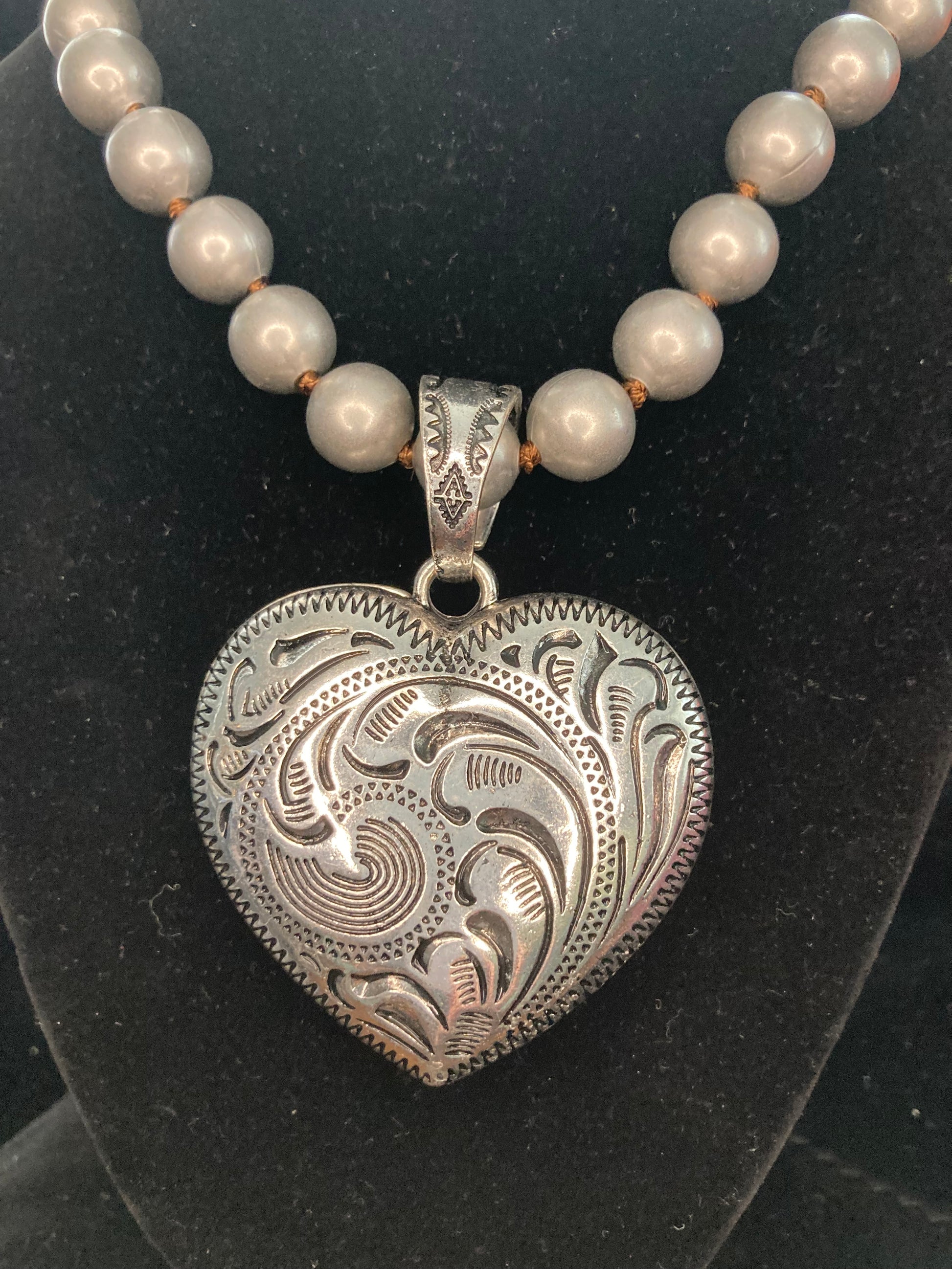 Necklace with a silver heart-shaped pendant and Silver beads on a black background
