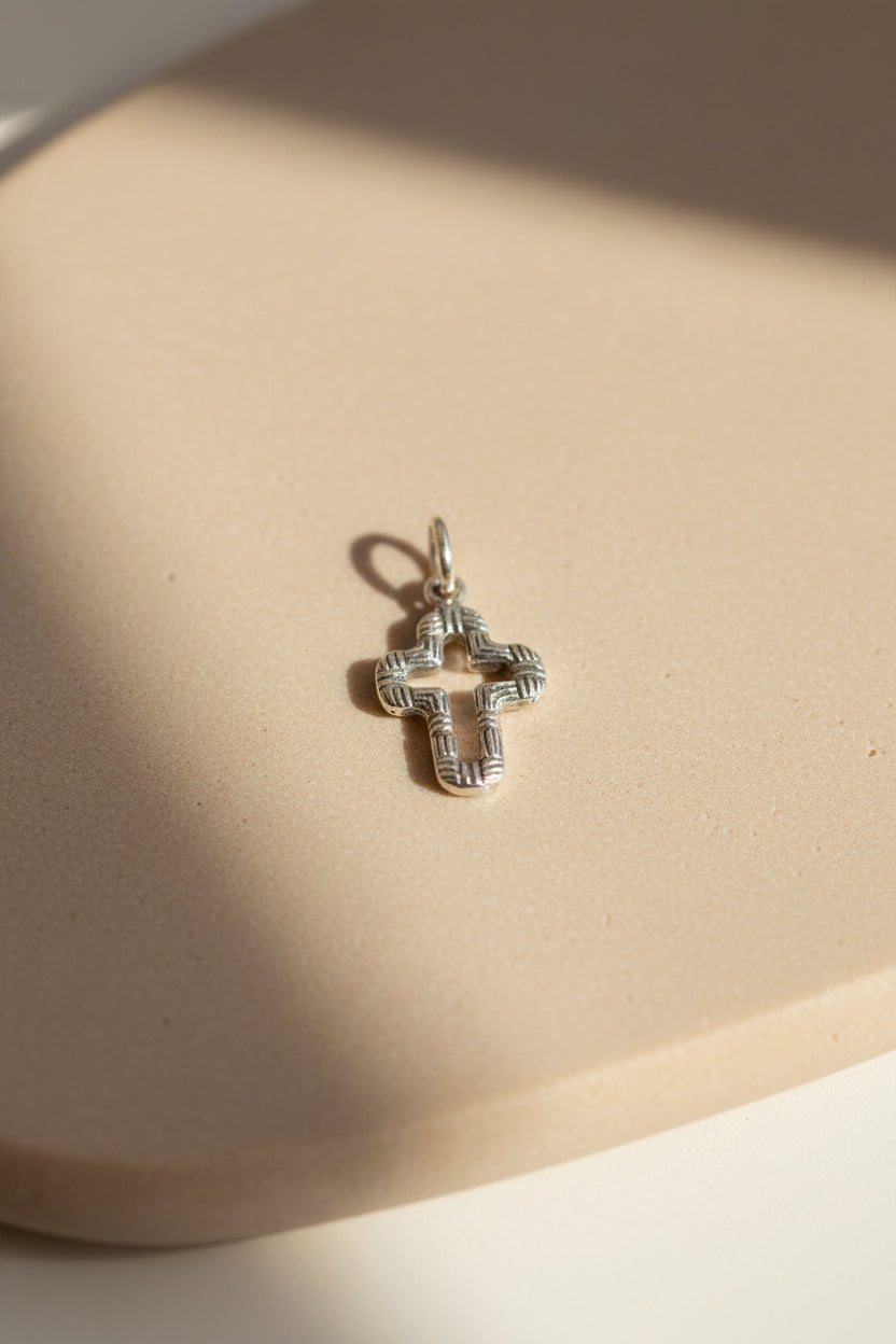 Silver cross charm on light background