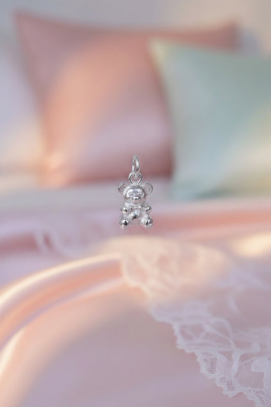Silver teddy bear charm on a beige background
